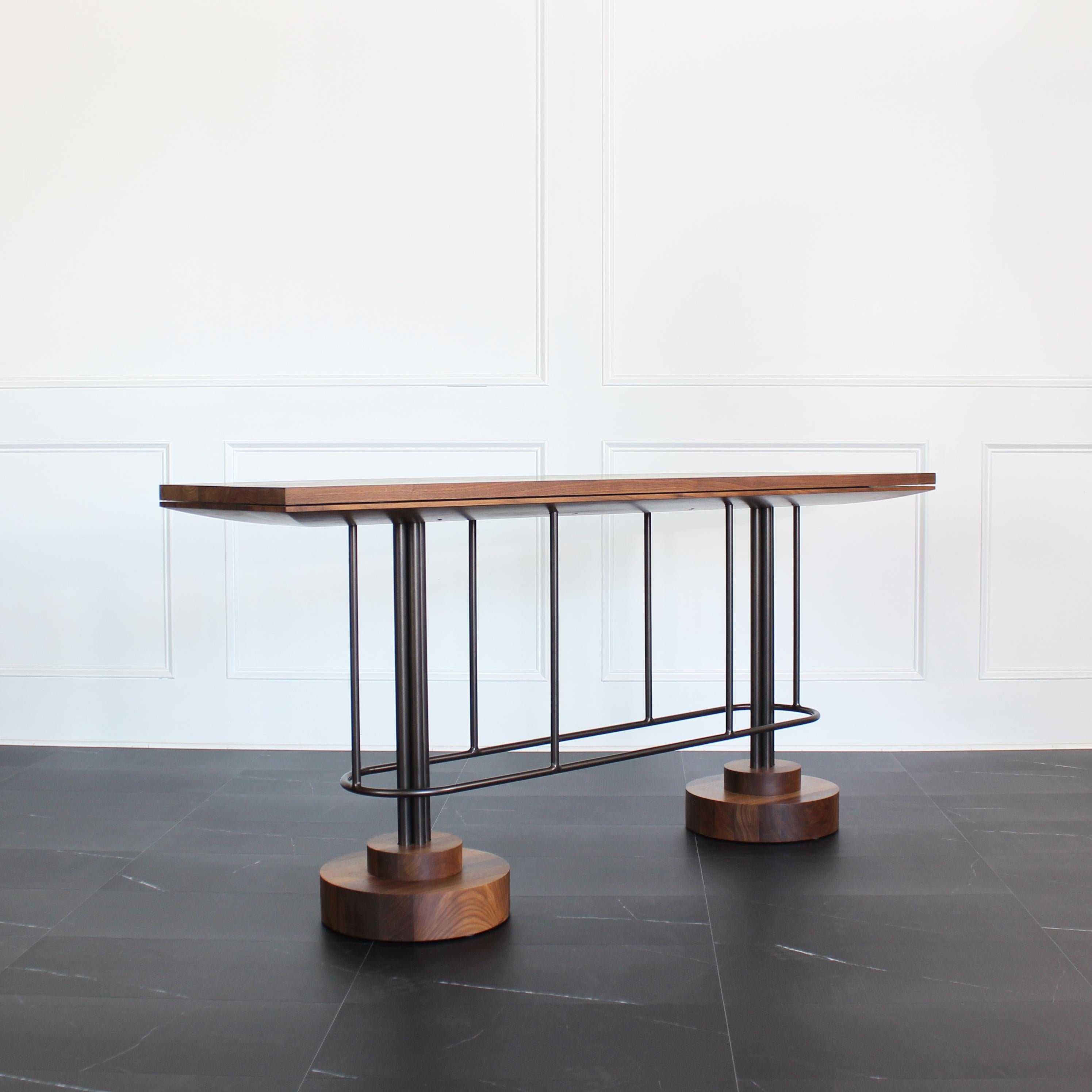 Inez console table by Crump and Kwash 

Solid wood top with carved under cap / hand rubbed oil finish / solid steel legs and footrest / durable powder coat finish / solid wood tiered bases / nylon glides 

Available in the following options.
