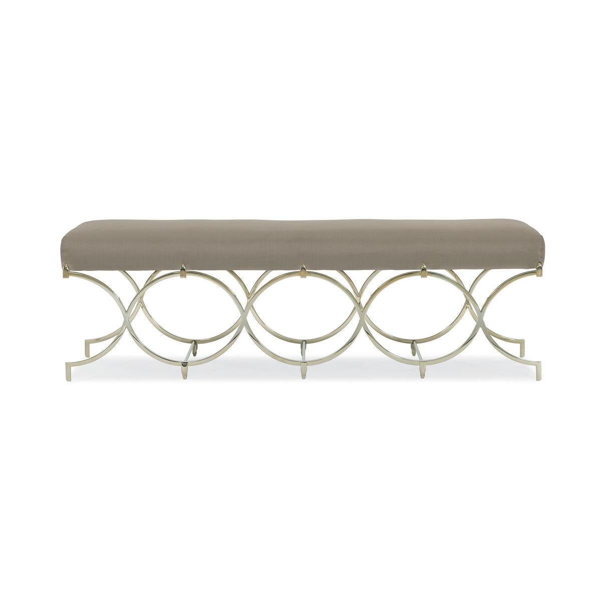 Swirling with Infinite Possibilities are intertwining Whisper of Gold metal rings that create the sculptural base of this exquisite bench. Covered in a dark taupe fabric with the softness and sheen of silk, this piece adds just the right amount of
