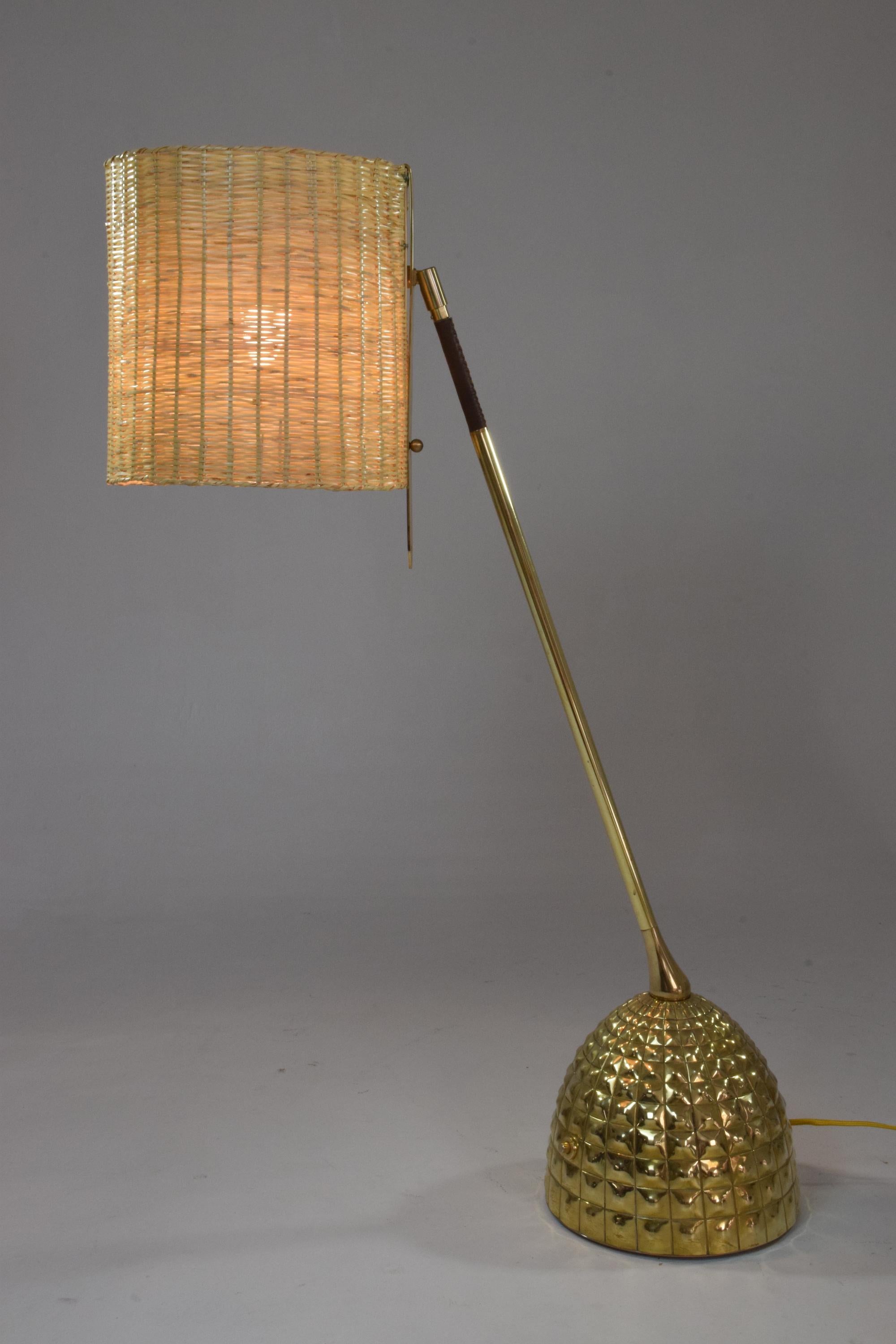 Contemporary handcrafted articulating table lamp pictured in a polished solid brass finish, adorned with a brown hand sewn sheathed leather detail by artisan saddle makers and a hand embellished base. The lamp is designed with our signature pear