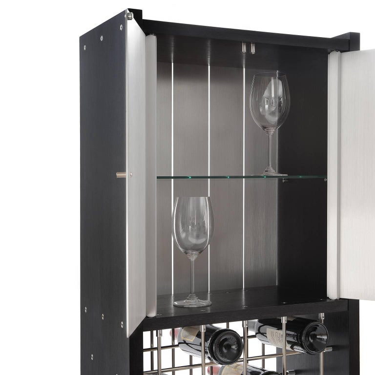 The Infinity wine cabinet holds 28 bottles of wine and storage for an array of glasses. It features a mesmerizing grid of stainless steel rods. These rods create a sculptural latticework that just happens to hold 28 bottles of wine. Above is a sleek