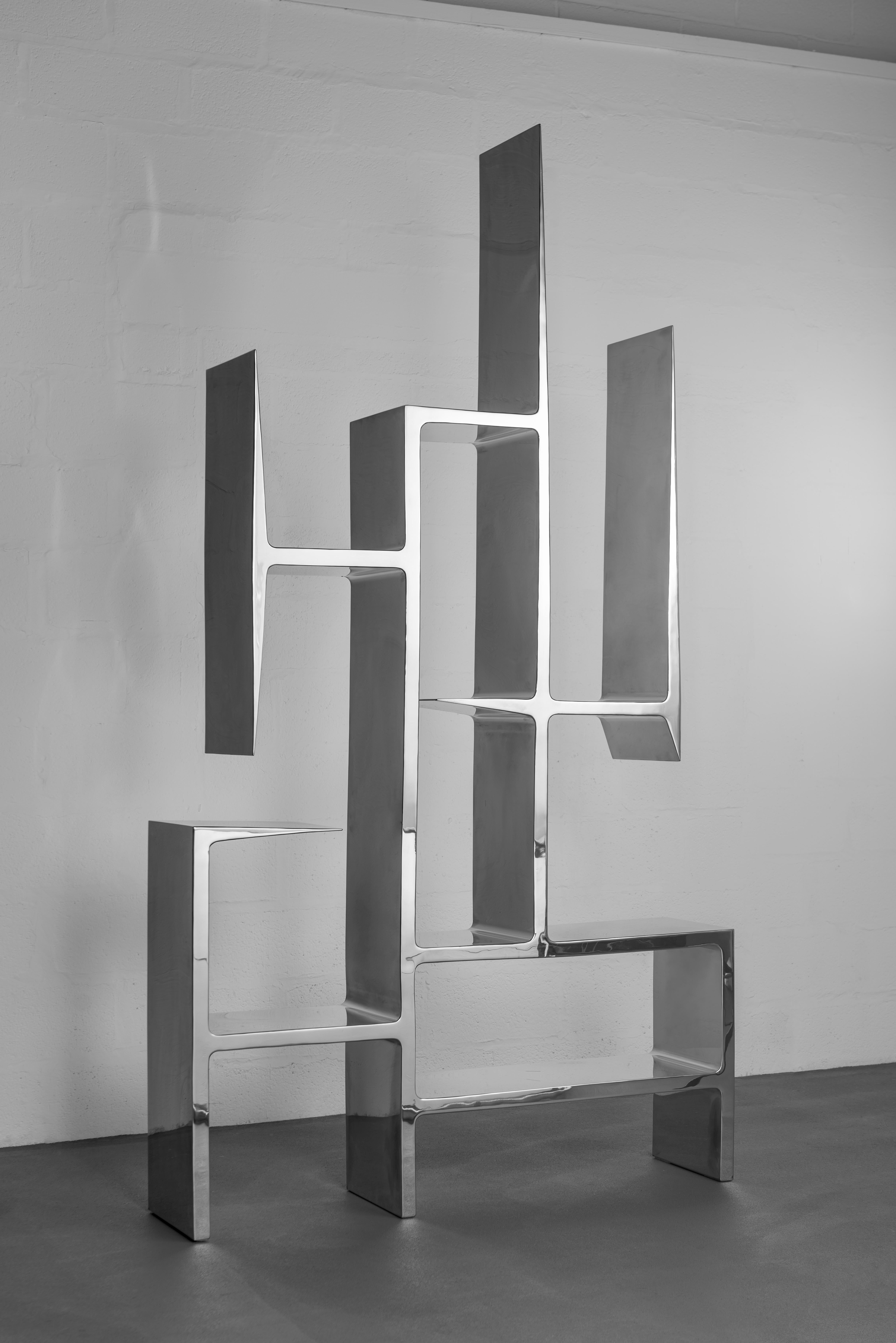 Libreria Infinity II di Pol Quadens 
Edizione limitata di 8+4 pezzi.
Dimensioni: D 30 x L 150 x H 220 cm.
Materiali: Acciaio inossidabile lucidato.

Pol Quadens è nato a Bruxelles. Suo padre era attivo nel campo dei compositi e dell'industria