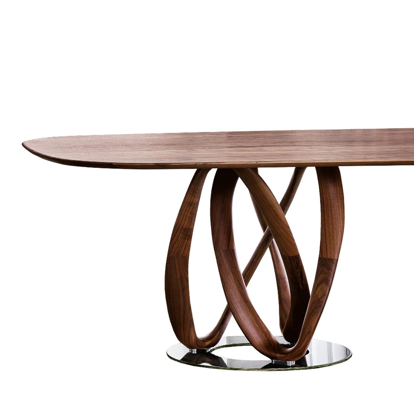 Table de salle à manger en noyer infini avec plateau en noyer massif biseauté 
des bords arrondis. Avec 2 pieds en noyer massif sculptés à la main avec
bases en acier en finition chromée.
Également disponible sur demande en :
L 280 x P 120 x H78