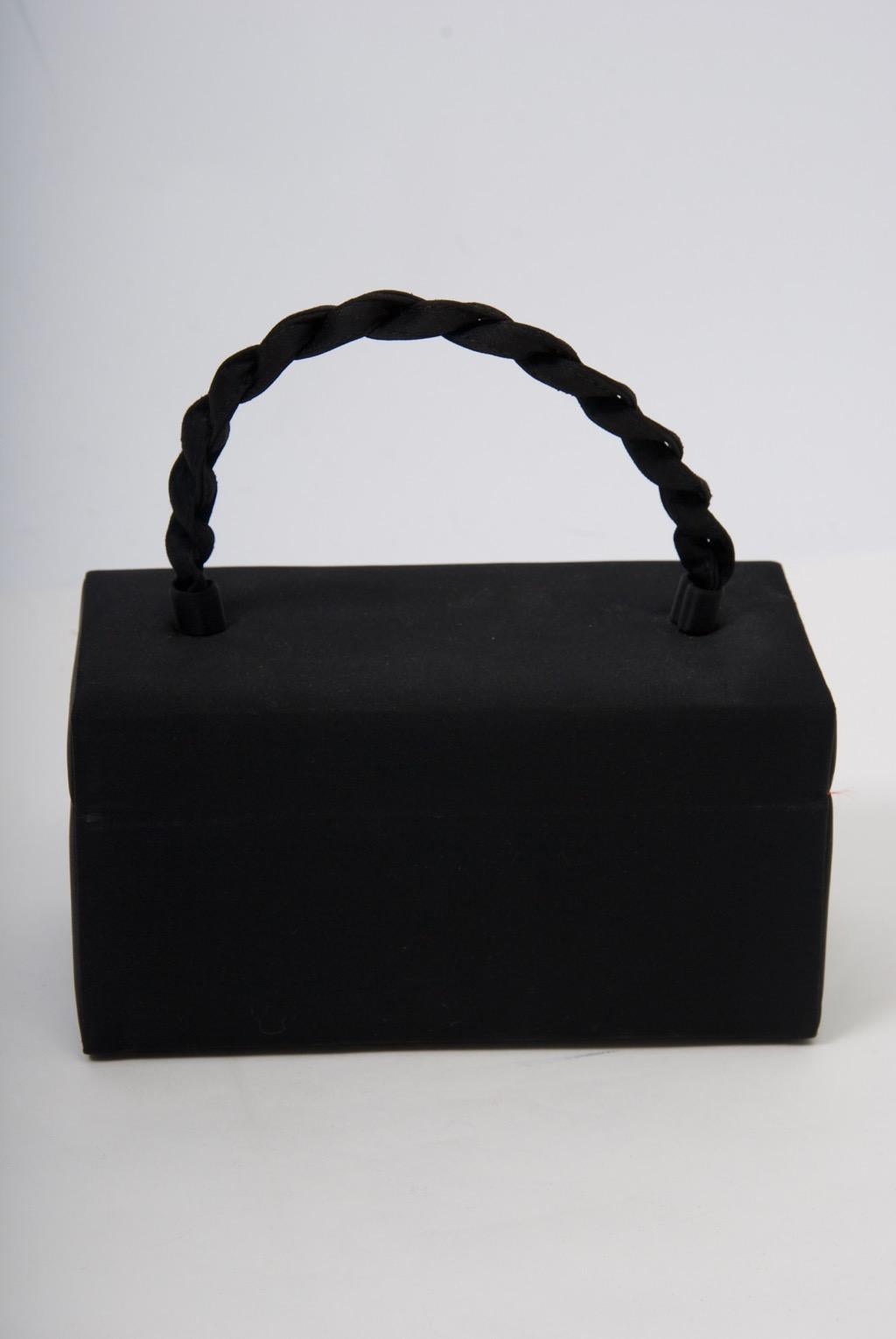 1960s Ingber box-shaped bag in black featuring a rope top handle and a jeweled clasp. Open to reveal a red interior with side compartment. Plenty of room for phone and essentials.
