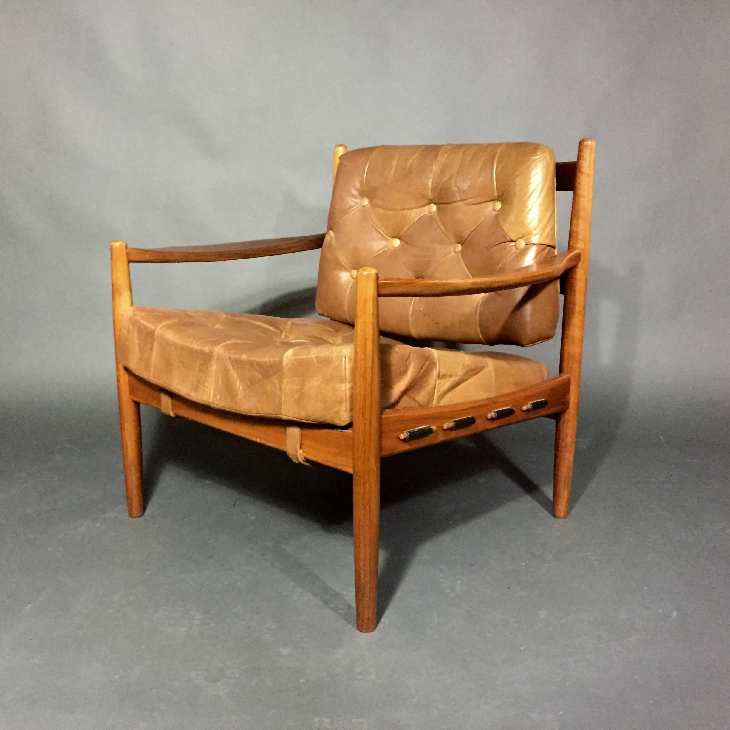 One of our favourite Thillmark chair designs. Beautiful patchwork and button tufted cognac buffalo leather over solid beech wood frame with sculpted arms. Seat is supported by black leather straps underneath that are secured with wood toggles on two