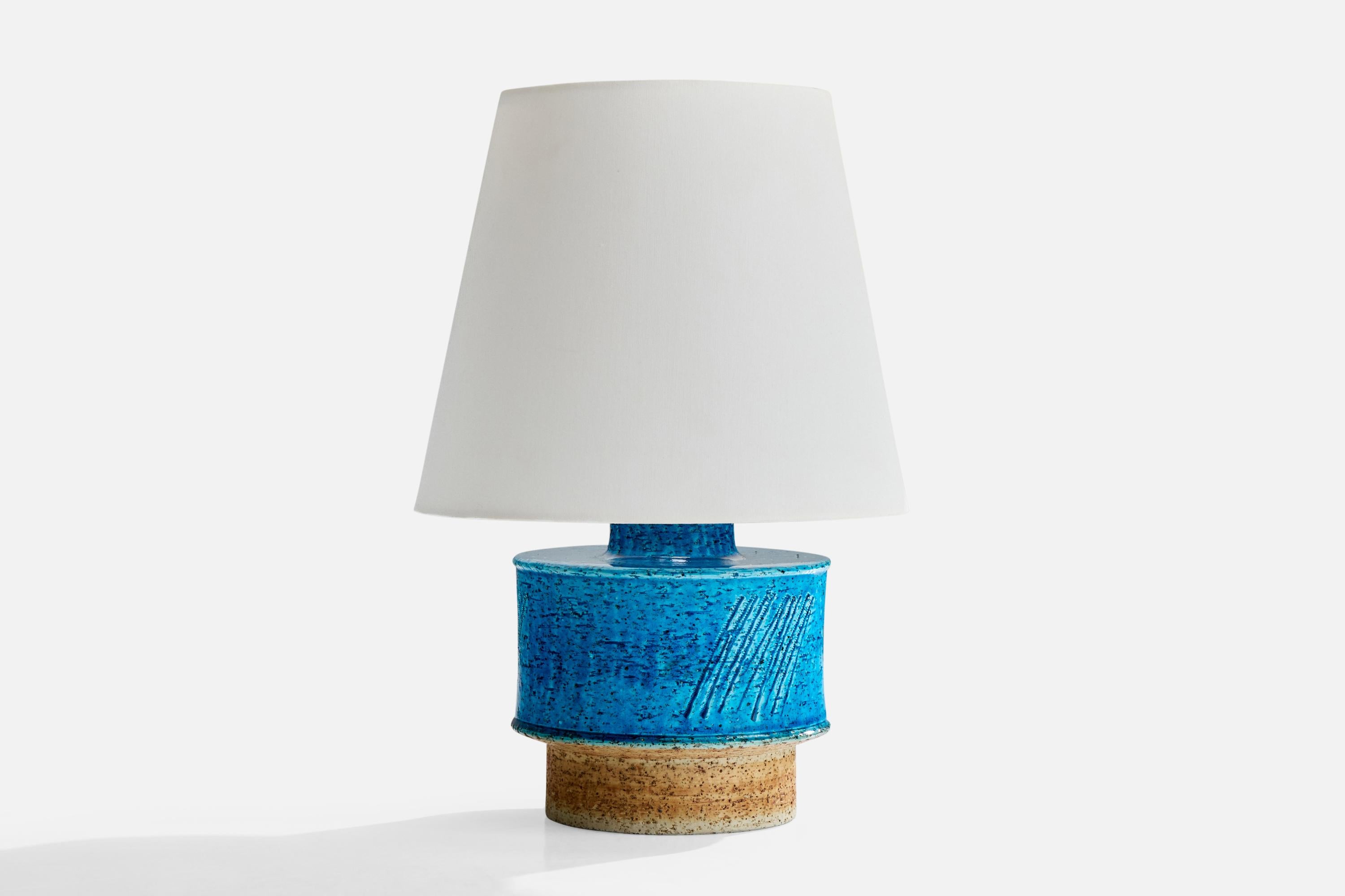 A blue and beige-glazed stoneware table lamp designed by Inger Persson and produced by Rörstrand, Sweden, c. 1960s.

Dimensions of Shade (inches): 5.5” Top Diameter x 8” Bottom Diameter x 6.75” Height

Dimensions of Lamp with Shade (inches): 11.75”
