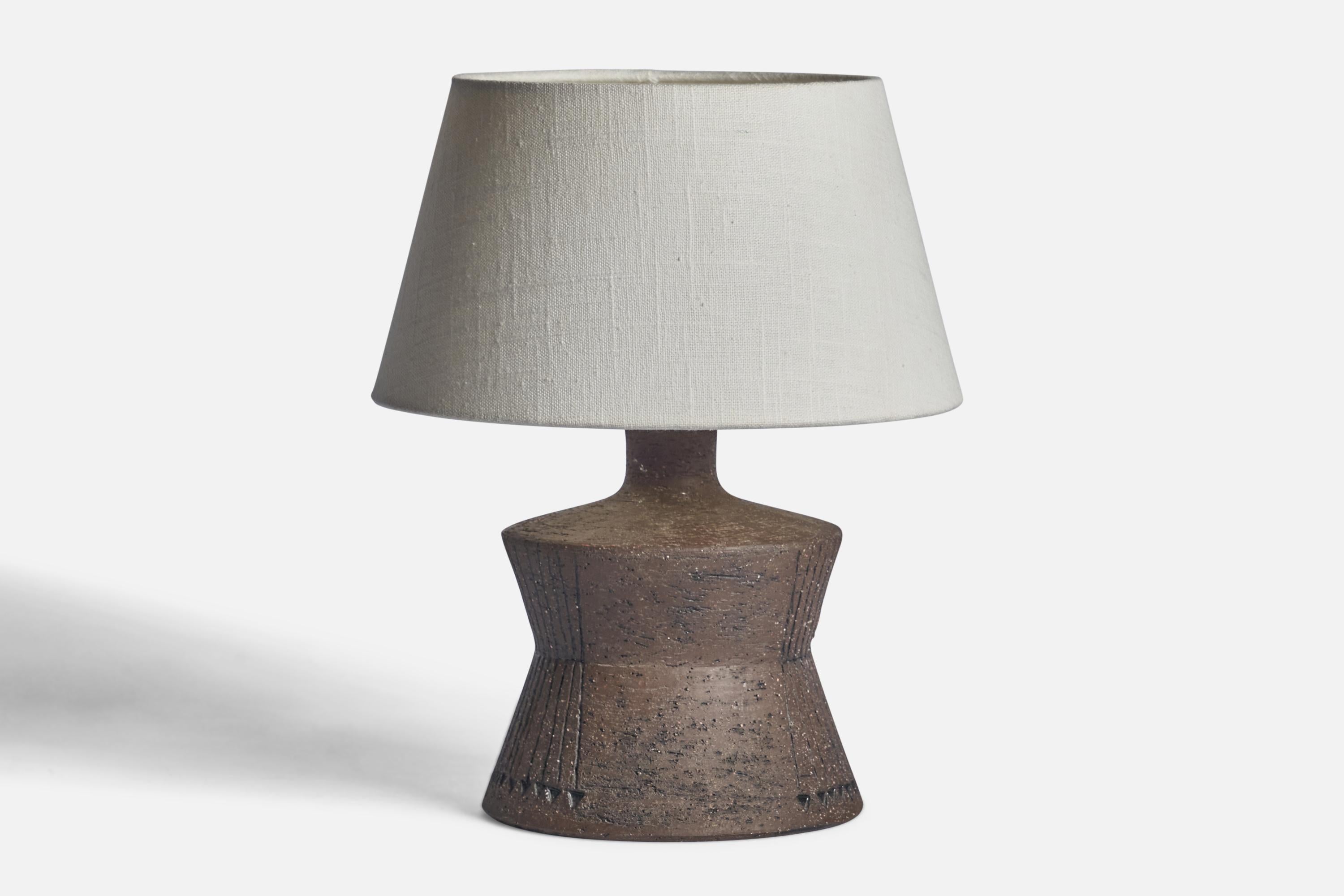 A grey-glazed incised stoneware table lamp designed and produced in Sweden, 1970s.

Dimensions of Lamp (inches): 9.25” H x 6.4” Diameter
Dimensions of Shade (inches): 7” Top Diameter x 10” Bottom Diameter x 5.5” H 
Dimensions of Lamp with Shade