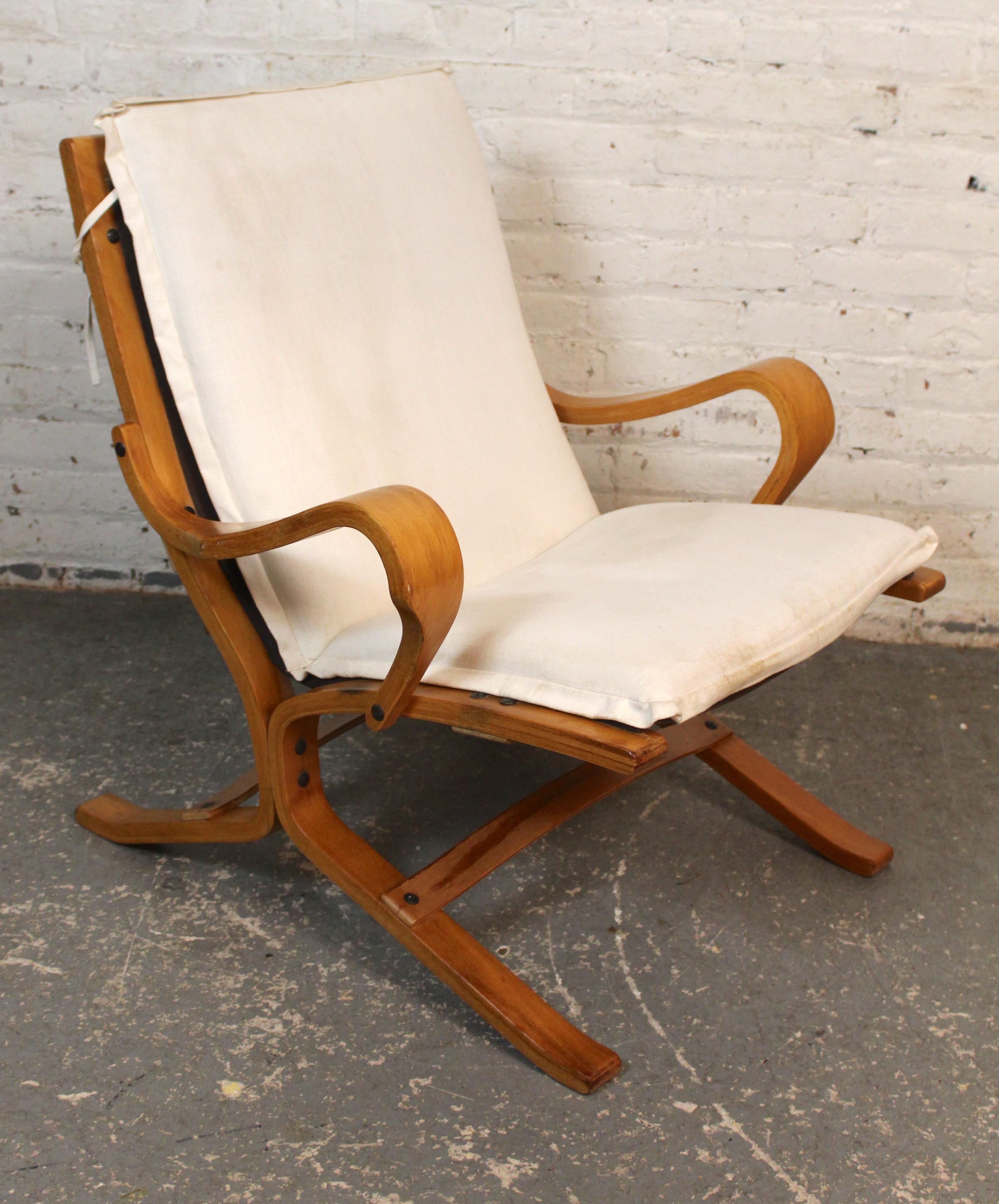 Este sillón de perfil bajo fue diseñado por Ingmar Relling y fabricado por Westofa Furniture. Con un diseño de madera curvada que permite que la madera fluya por todo el cuerpo, por los brazos y por las piernas separadas. Se añaden dos cojines para