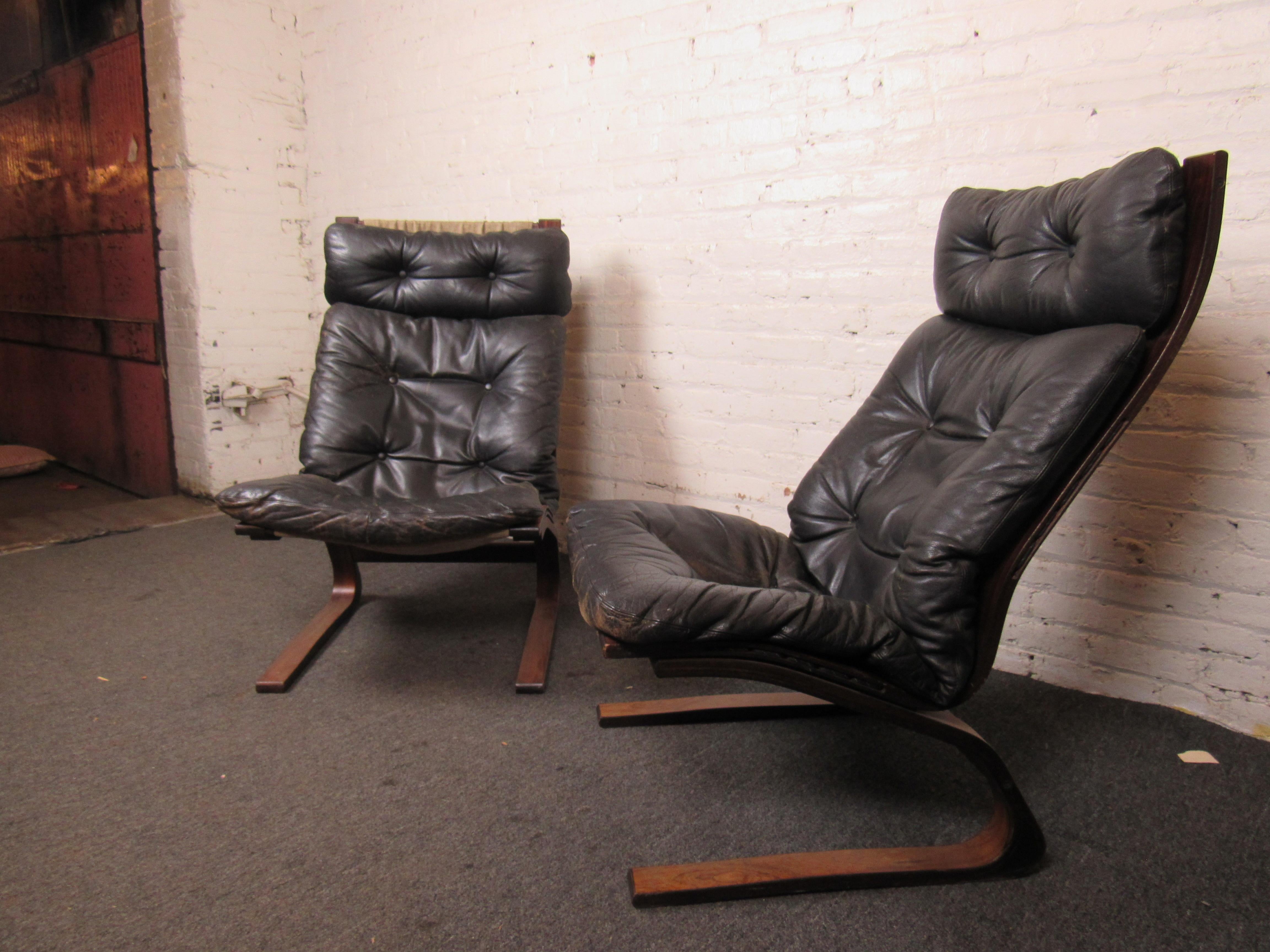 This pair of stylish lounge chairs combine black leather upholstery with walnut frames. Please confirm item location with seller (NY/NJ).