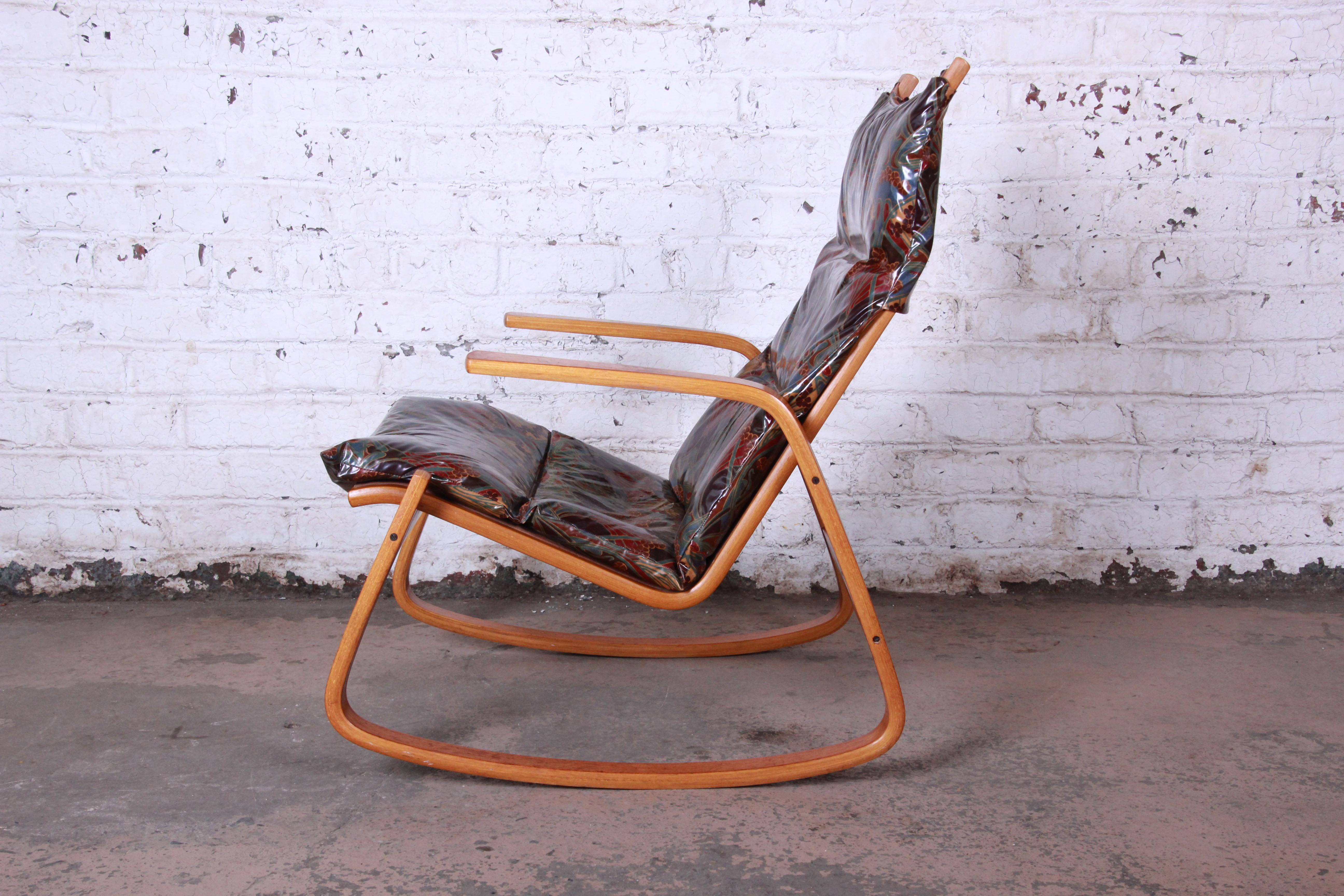 A stylish Scandinavian Modern teak rocking chair designed by Ingmar Relling for Westnofa. The chair features a solid teak bentwood frame and sleek Scandinavian design. It has the original paisley vinyl upholstery over canvas. Could be easily