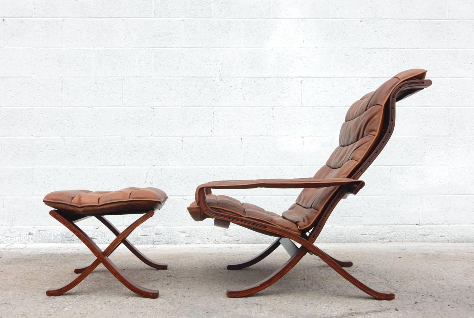 A pair of Ingmar Relling design for Westnofa Siesta leather lounge chairs plus ottoman.
Campaign style with folding frame and leather strap arms. Tall back,
Light brown leather cushions and rosewood finish on sculpted teak frames.
Exceptionally