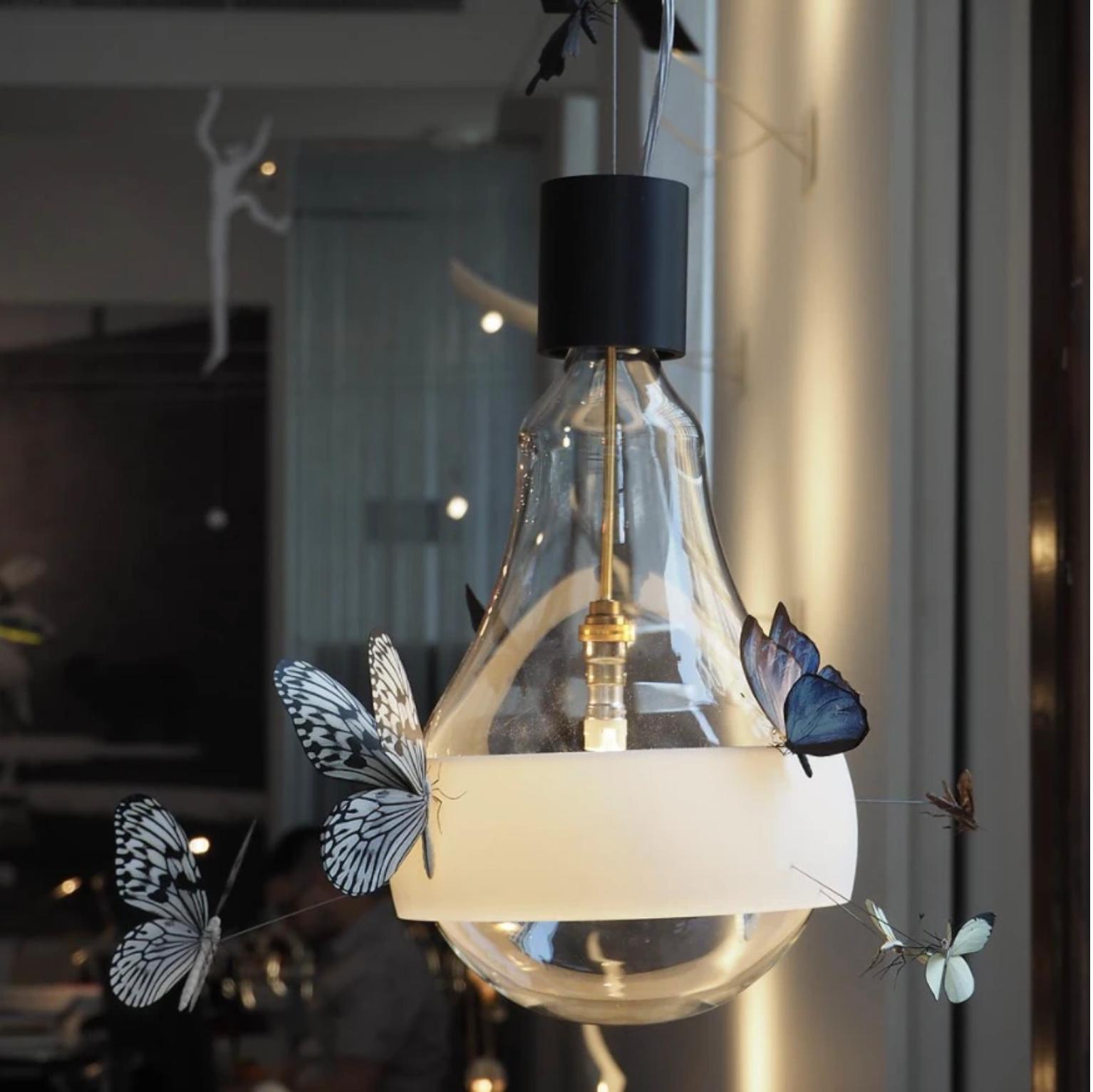 A very special piece by the poet of light, Ingo Maurer.
Ten hand-made butterfly models flit around the bulb on this suspension light. Flatterby is a limited edition of 200 pieces. The ring is a 3D printed part, the serial number is imprinted in the