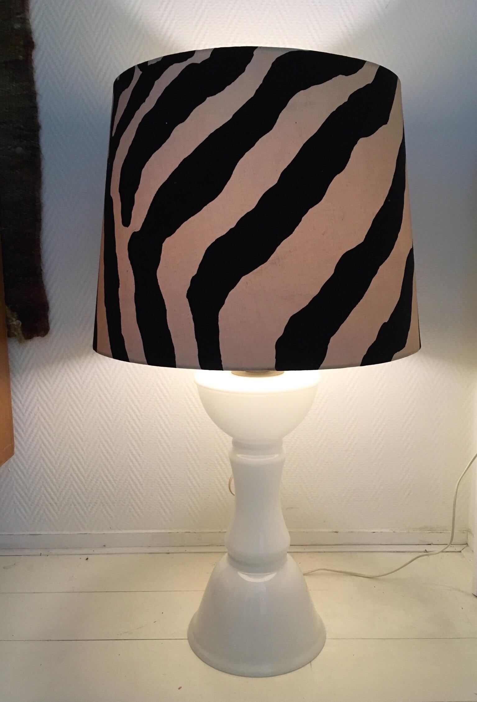 Seltene Stehlampe oder Stehleuchte mit weißem Glassockel. Der originale Schirm mit Zebradruck weist einige Gebrauchsspuren wie Verfärbungen, einige Flecken und Dellen auf. Immer noch ein sehr begehrenswertes Stück! Mit dem Aufkleber des Herstellers