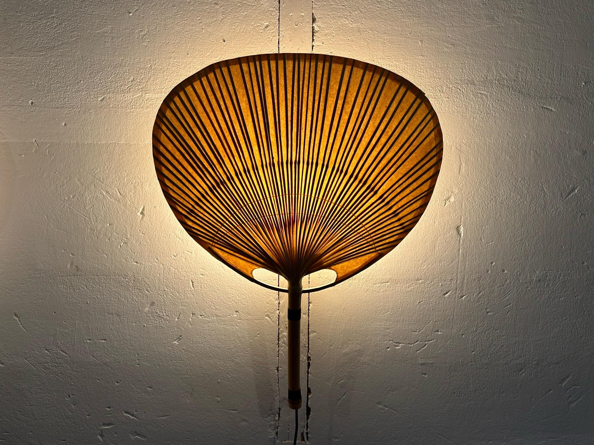 Incredibl model Uchiwa 3 wall scone designed by Ingo Maurer, Germany 1973. The shades, made of bamboo and rice paper, give off amazing warm light. These lamps are all hand made and one of the most iconic designs by Ingo Maurer. With these beautiful