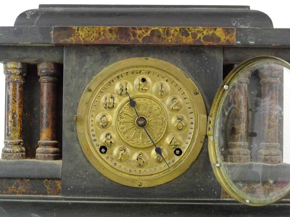 The Ingram mantle clock has a black stained wood casing, a gilt metal face with two sockets for winding by key (missing), faux marble columns, metal feet and a circular brass cover for opening in the back. Inside are the spiral movements and a