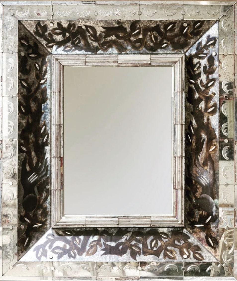 Un gran espejo rectangular de cristal con marco de estructura de roble. El marco está decorado con un motivo orgánico estilizado de hojas y vides. Esta decoración se ha conseguido mediante el método 