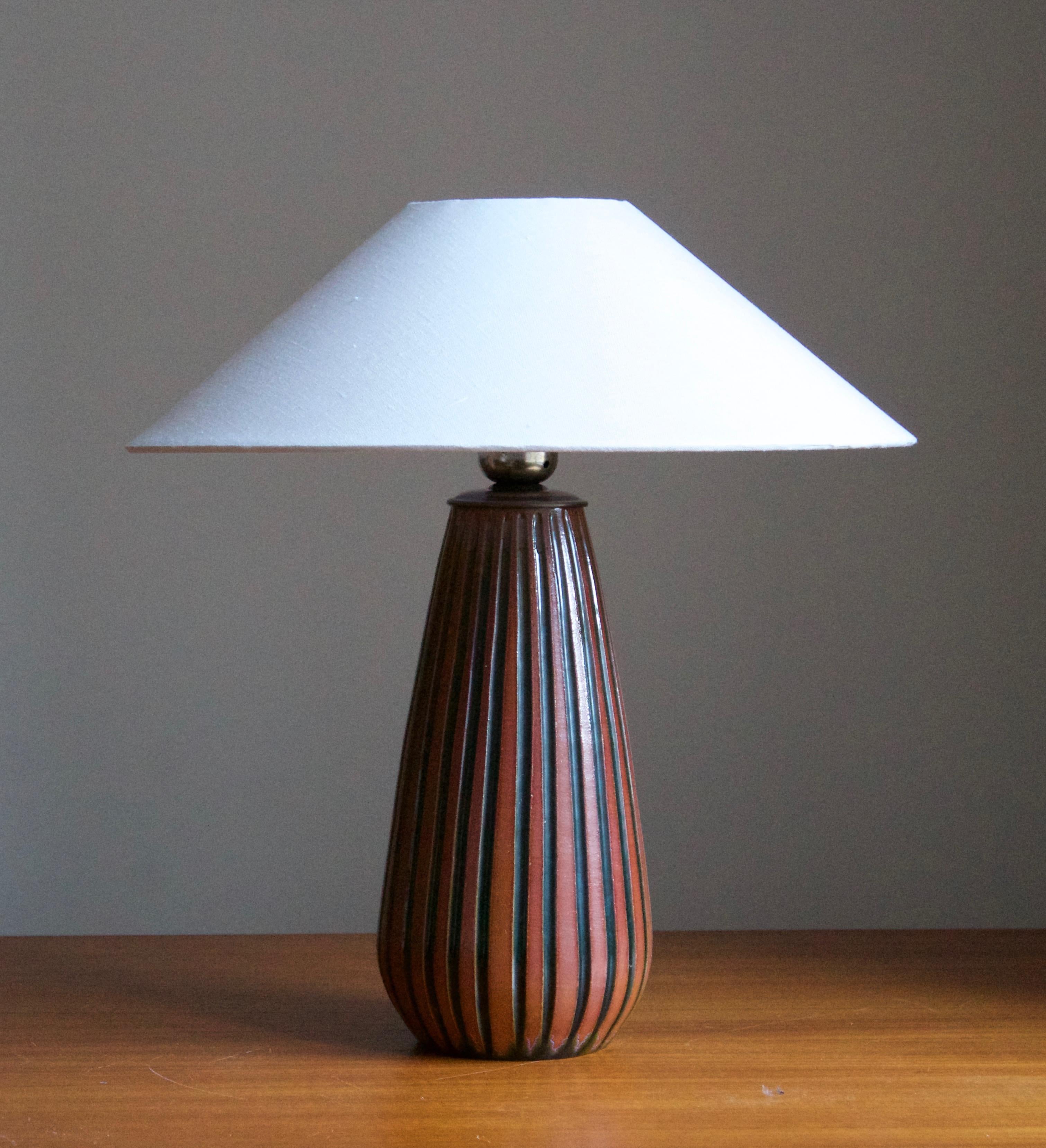 A table lamp, on a fluted black / red ceramic base designed by Ingrid Atterberg for Upsala Ekeby, Sweden, 1950s.

Sold without lampshade. Stated dimensions exclude lampshade. Height includes socket.

Glaze features a brown color.