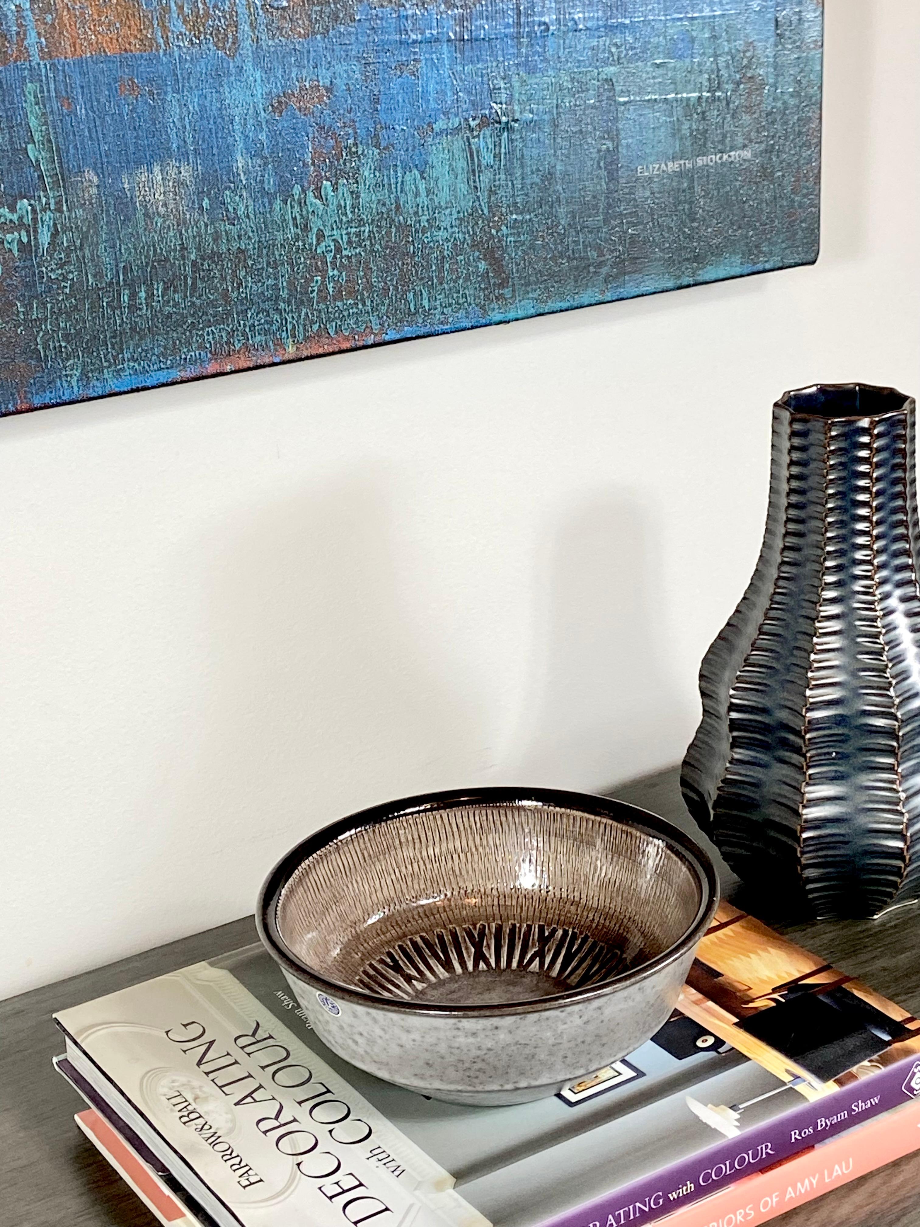 This beautifully incised Mid Century bowl is by Ingrid Atterberg for Upsala Ekeby Sweden. It was hand glazed and hand carved in the 1960's. It's glazed in a latte, mottled grey and brown finish with a brown trim. The interior design has quite a bit