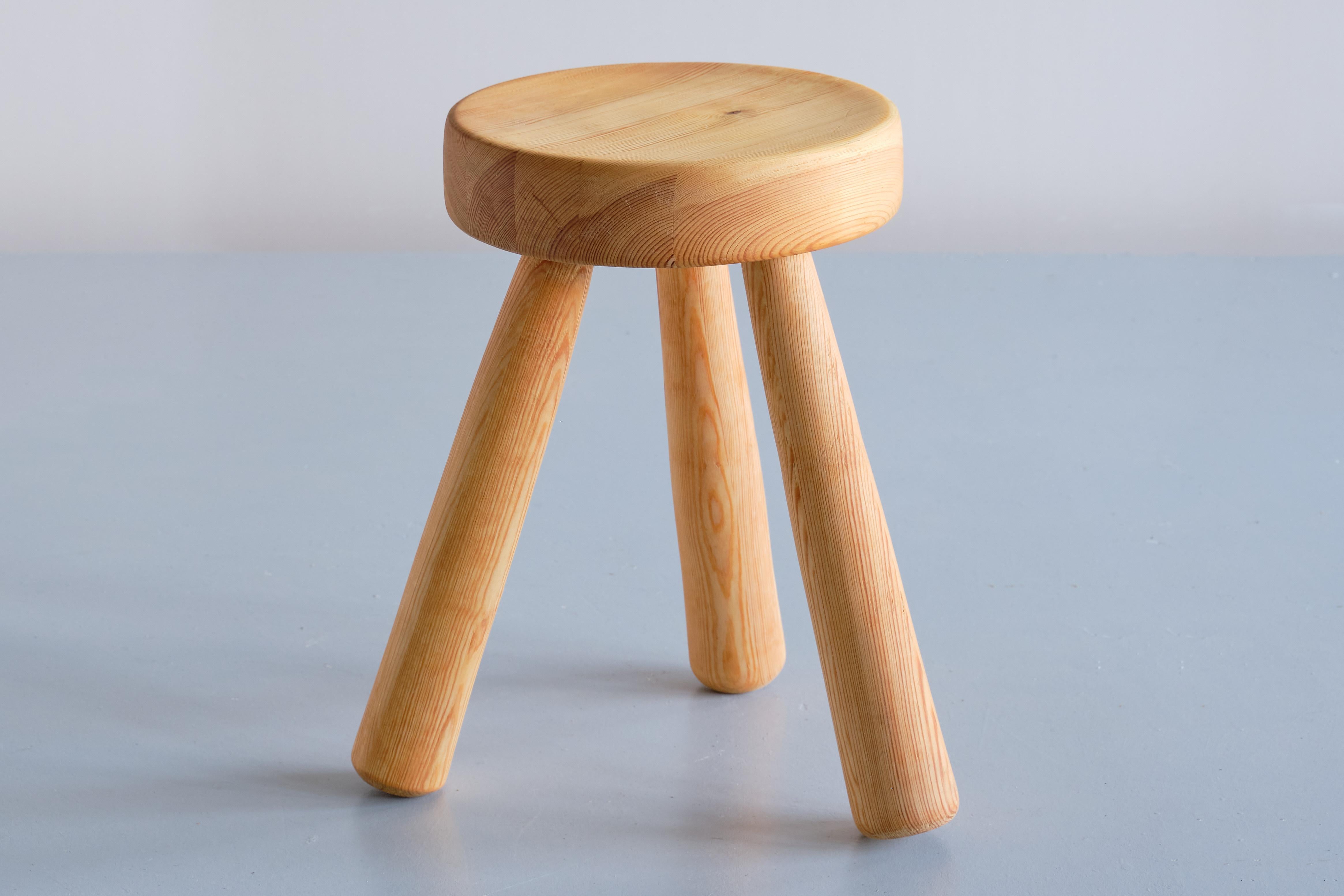 This rare stool was designed by Ingvar Hildingsson and produced by his company IH Slöjd in Rockneby, Sweden in the 1970s. The stool has a round seat and three club shaped legs, all in solid Swedish pine wood with a beautiful distinct wood grain. The