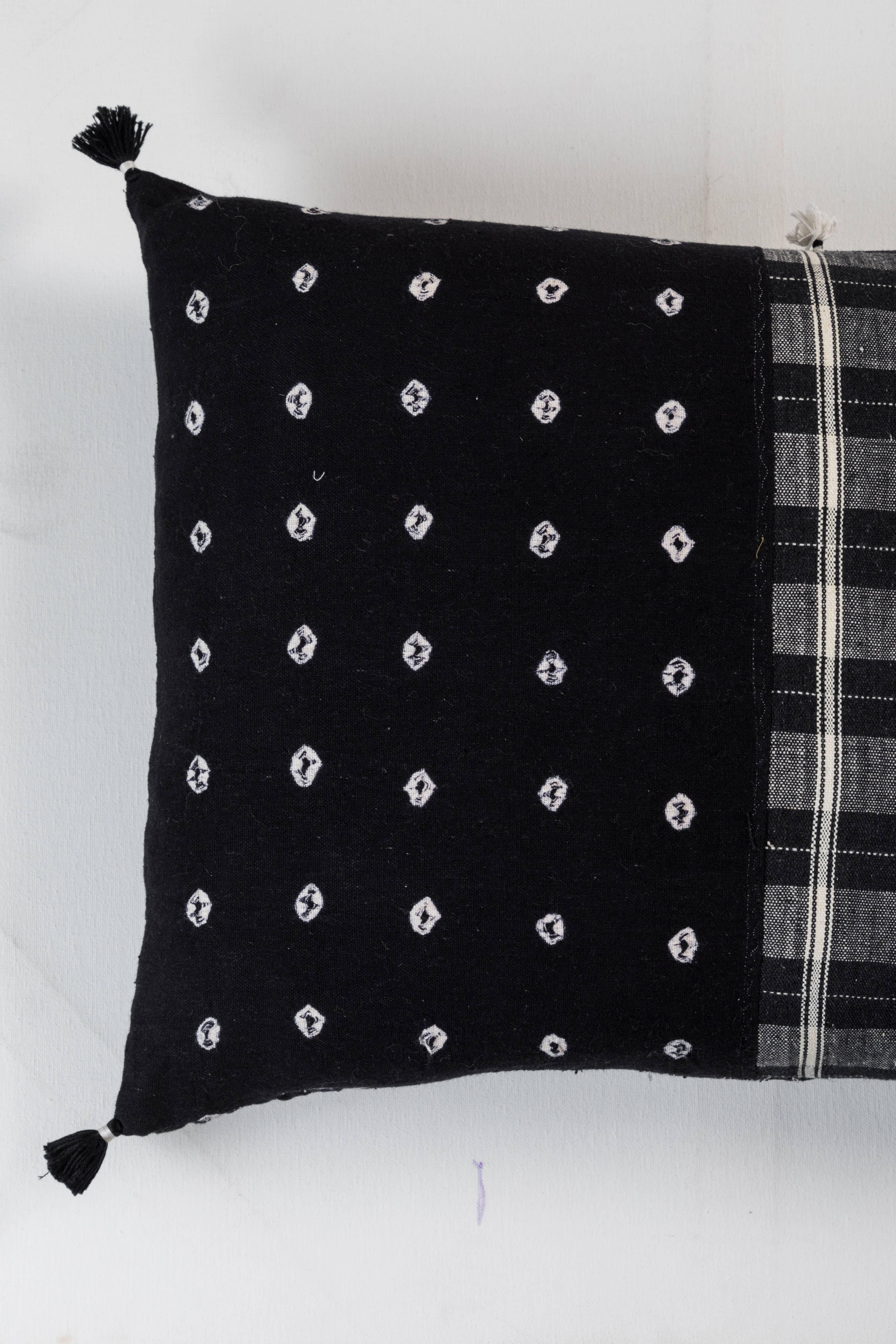 Kala naturally dyed organic cotton from Gujarat, India.  Hand-loomed using traditional Indian textile techniques to produce extra weft woven stripes and plaids.  This black and white pillow has added hand-knotted tassels. Areas of hand embroidery