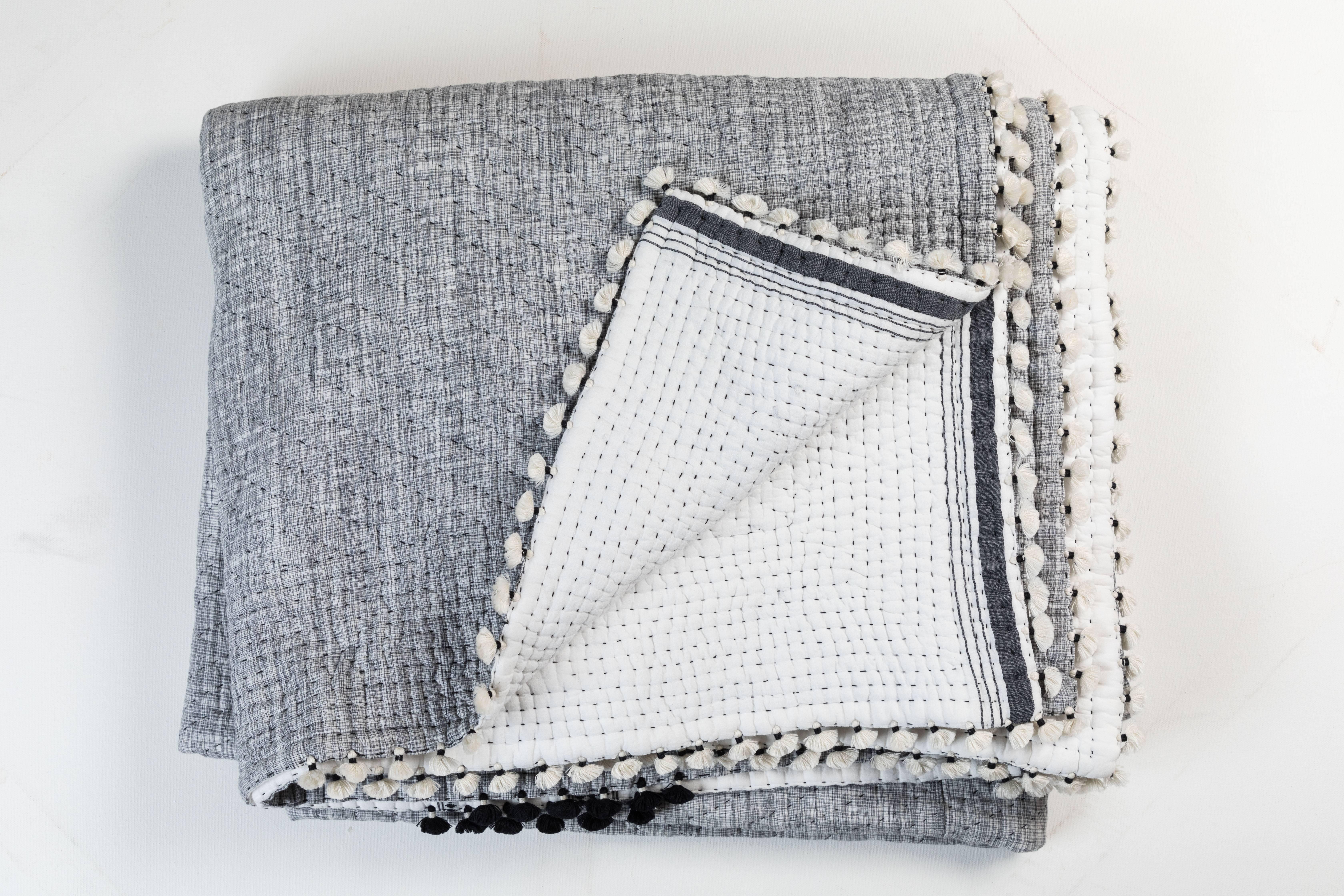 Kala naturally dyed organic cotton from Gujarat, India. Hand-loomed using traditional Indian textile techniques to produce extra weft woven stripes and plaids. This grey, white and black hand stitched quilt has added hand-knotted tassels.       