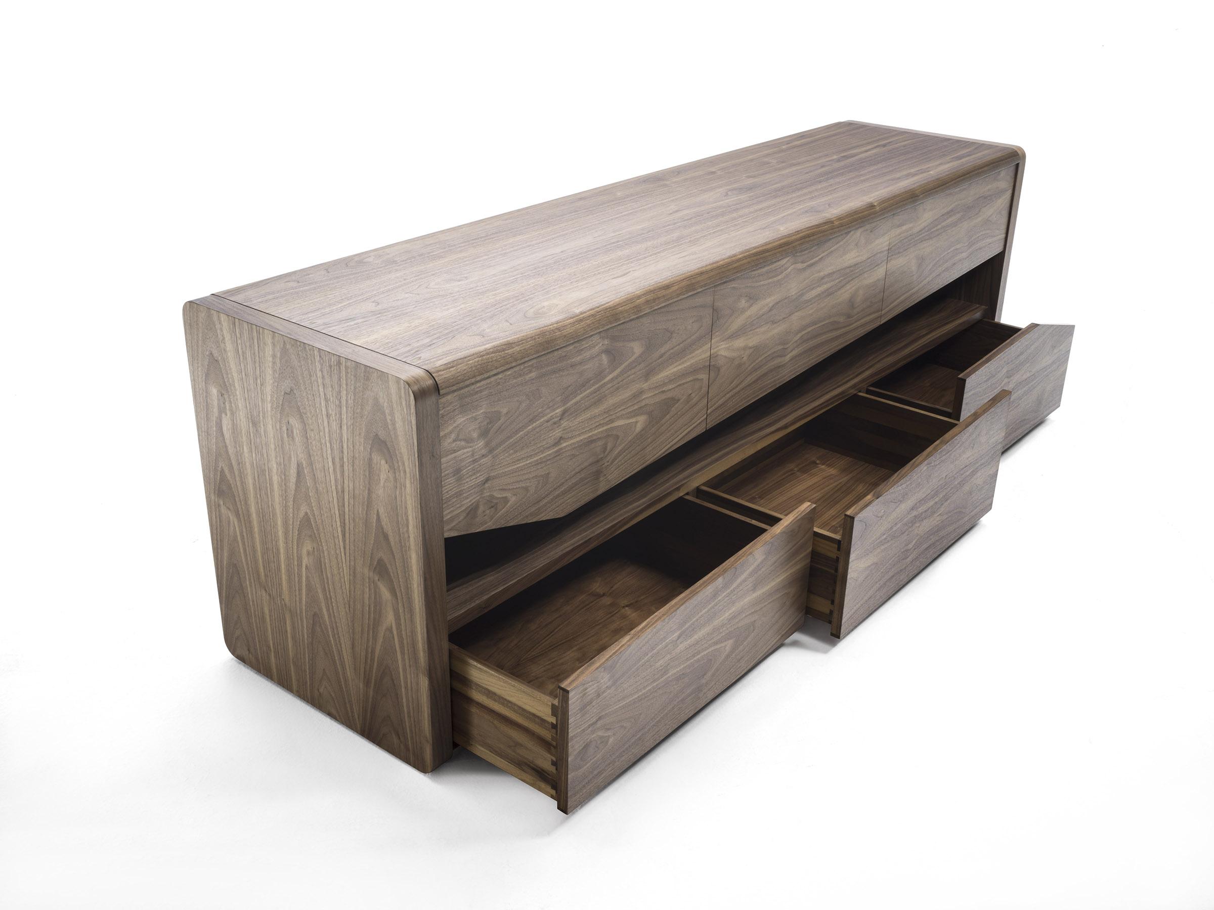 Sideboard in solid and multilayer wood, characterized by rounded sides and top that surround the 6 drawers, assembled with dovetail joints and equipped with shaped fronts. A central open space divides the two rows of drawers.

Available in walnut