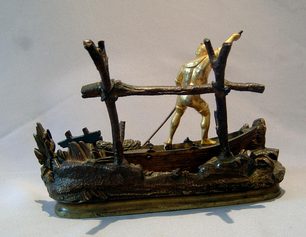 A good Italian Grand Tour model of a Neopolitan fisherman at his work. In ormolu and patinated bronze the oval base is naturalistically decorated with rocks and seaweed which the fisherman is working his clinker built boat through with a boathook.