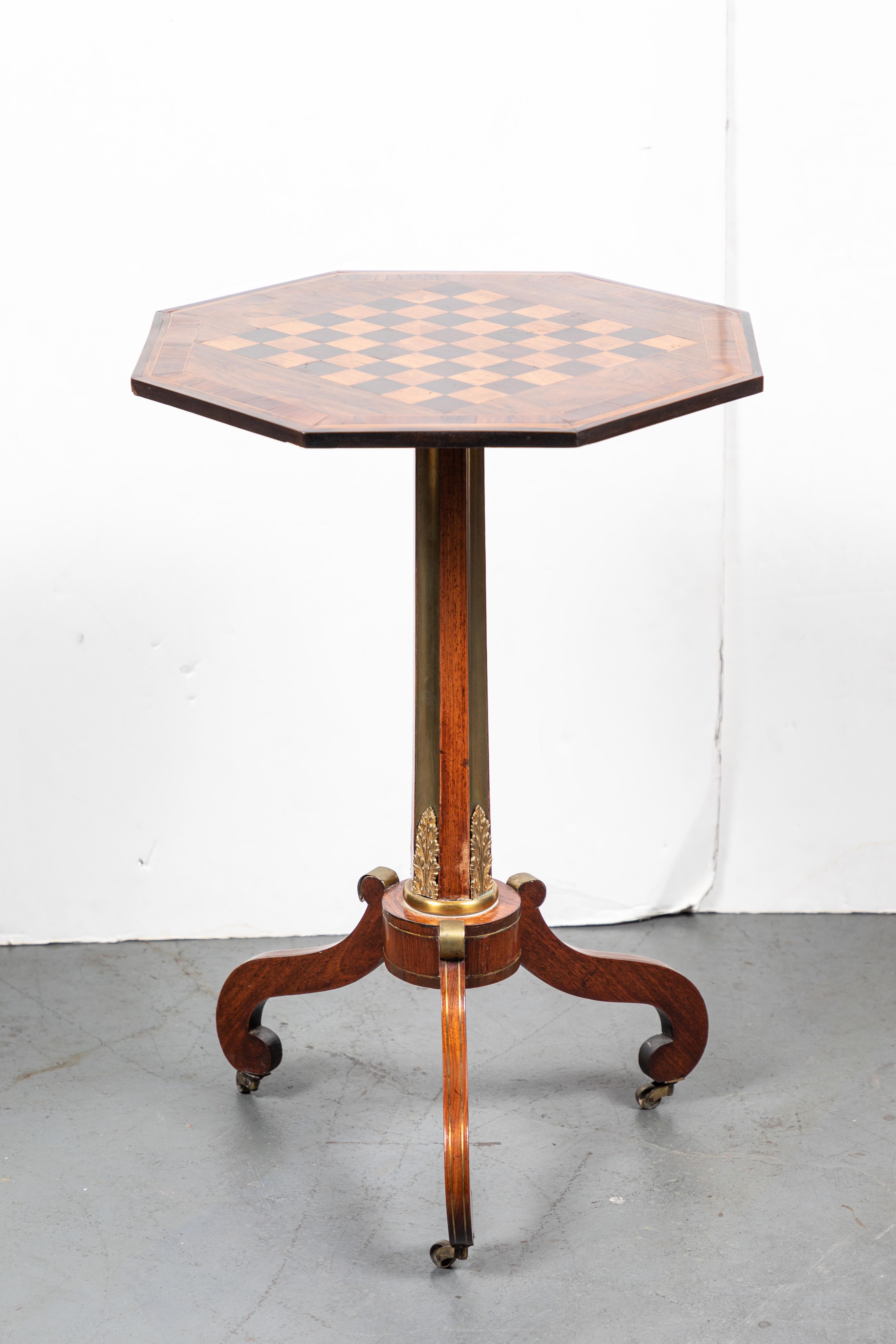 Handsome, hand carved, veneered and inlaid, walnut and mahogany, octagonal pedestal table. The checkerboard embellished top above a column inset with gilt brass, and mounted on three, serpentine legs inlaid with brass veins and terminating in