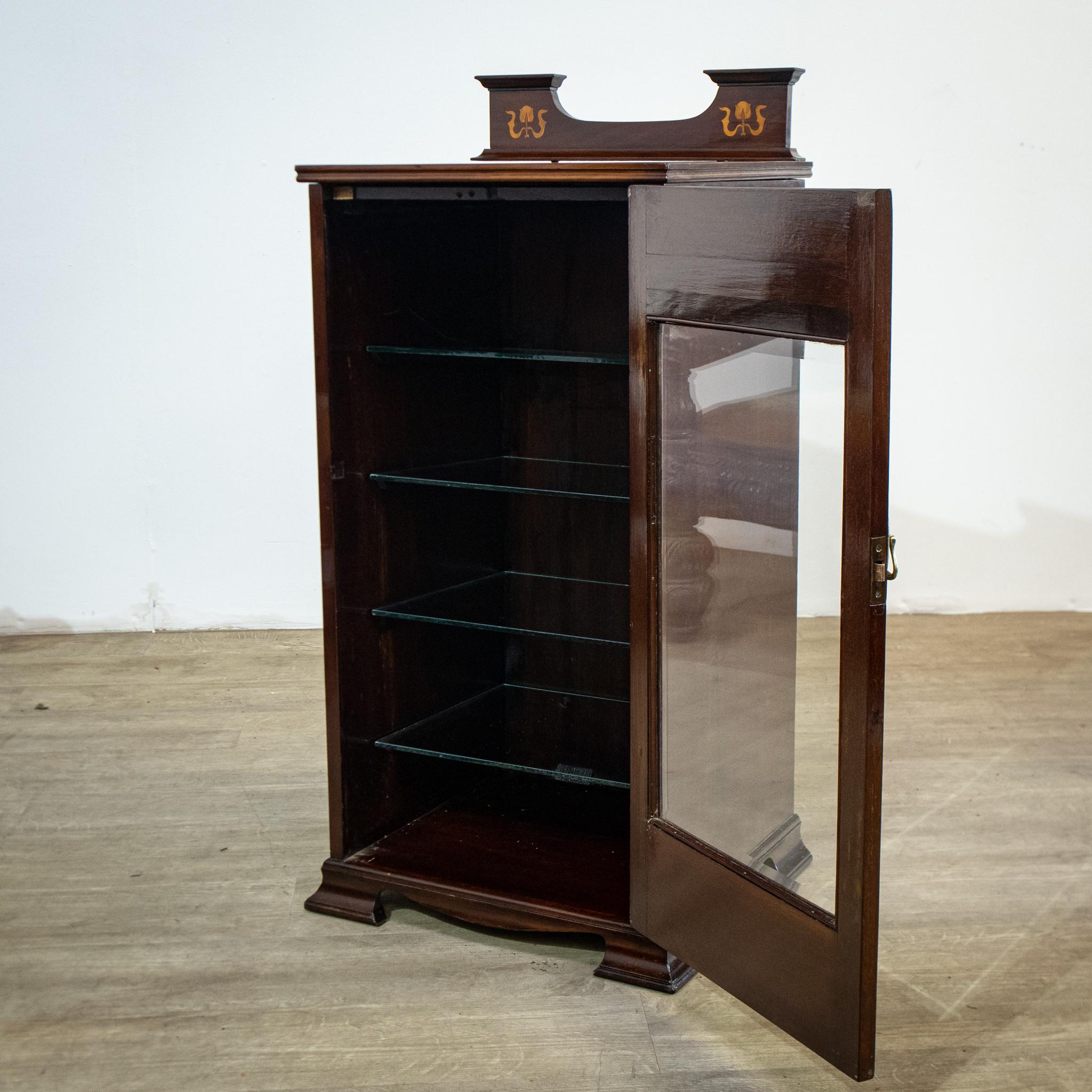 This lovely Edwardian glazed display cabinet has some beautiful inlaid Art Nouveau flower designs to the door and in the raised gallery at the back. The piece has recently been refinished to make it ready for the home, and has been provided with
