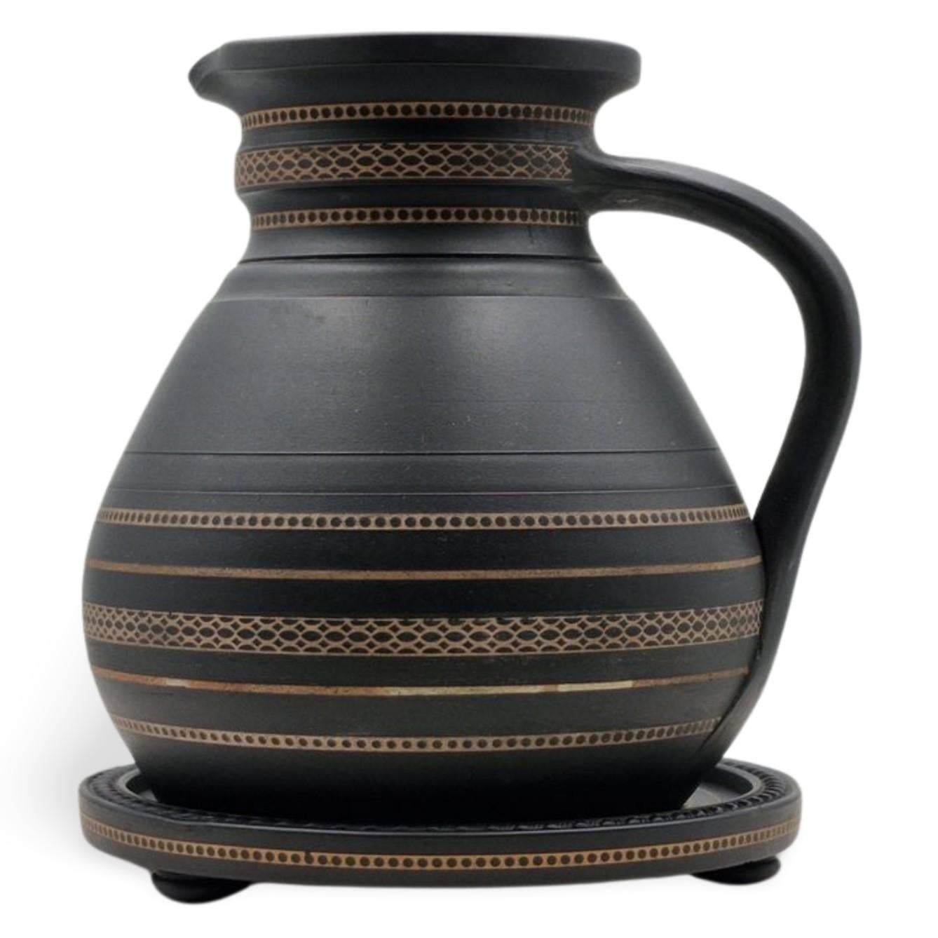An ale jug and matching tray, in black basalt with inlaid coloured decoration; a style known as Henri Deux. This stylle is a revival of an 18th century technique, in which designs are pressed into the clay, then filled with coloured slip, or liquid
