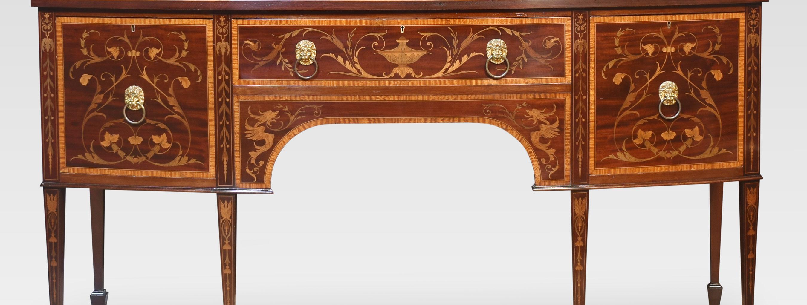19th-century Mahogany inlaid sideboard with large rectangular bow-front top having satinwood cross banded edge above are central inlaid drawer having brass lion handles, flanked by a cupboard on one side the other fitted with a cellaret. All raised