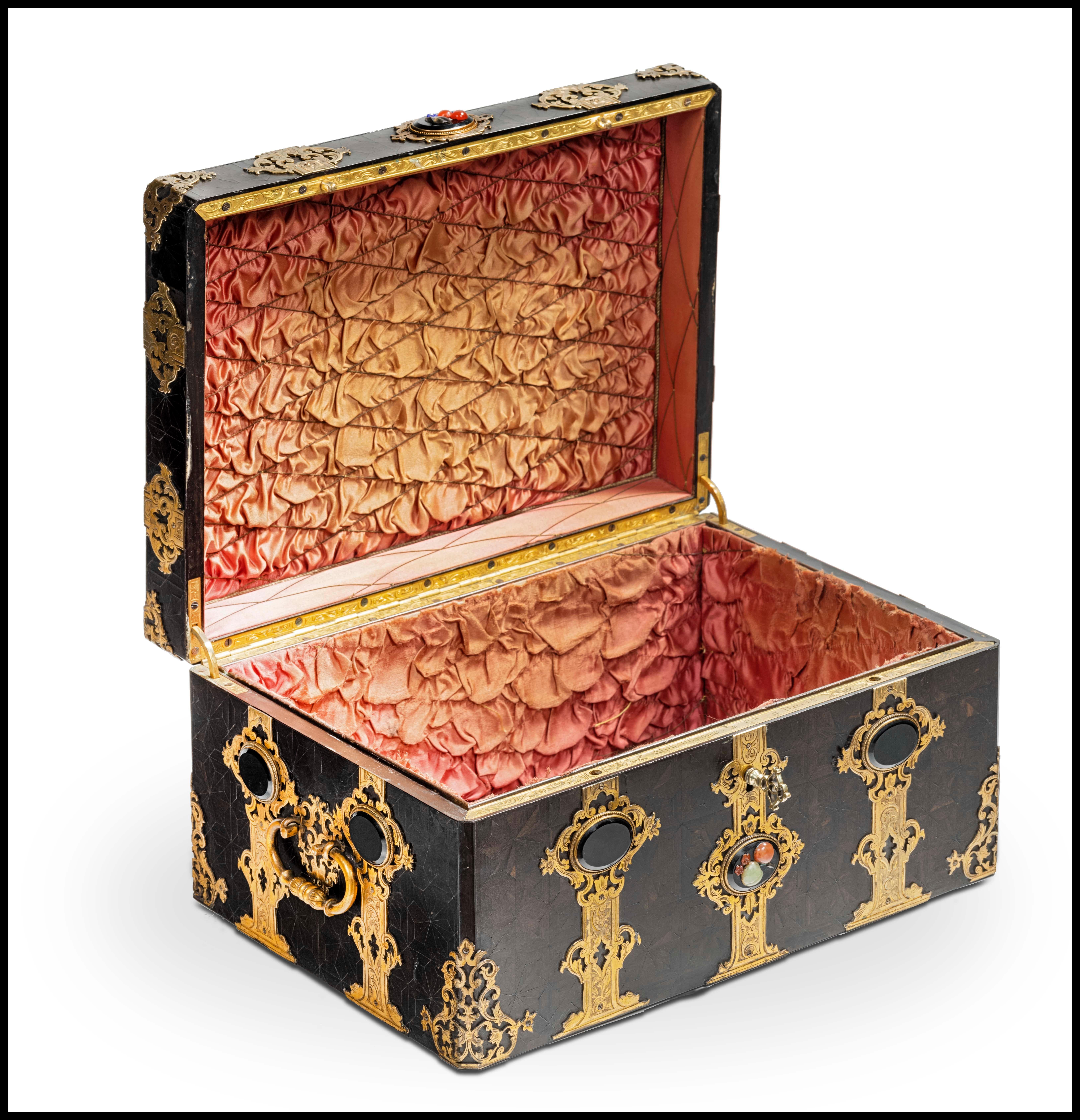 Rectangular box in ebony veneer inlaid with star patterns, all sides and the cover adorned with finely openwork and chiseled hinges in gilded bronze set with hard stone cabochons, side handles. 
Original key. Interior upholstered in silk.

First