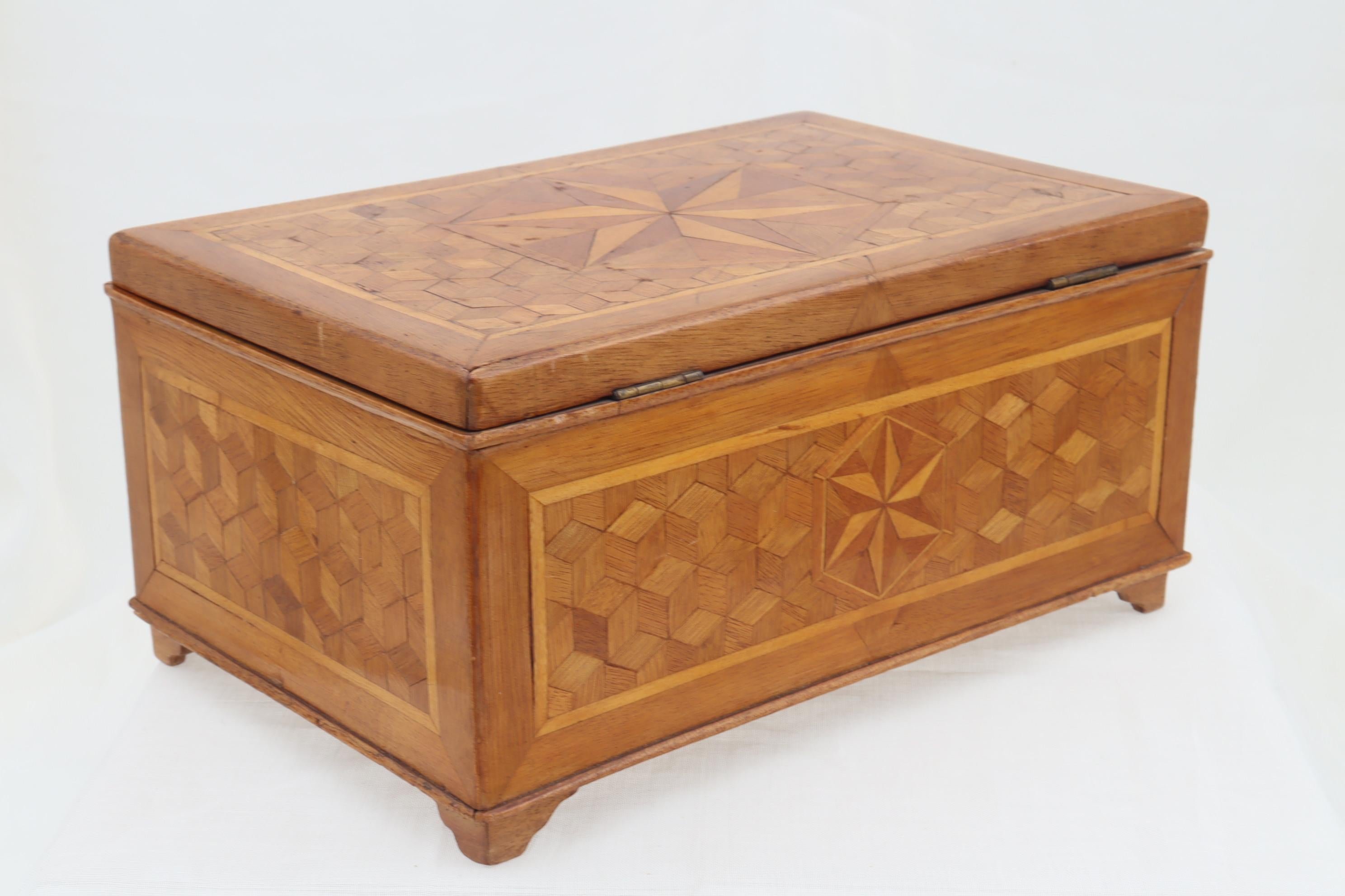 This well made wooden box was made in the Harderwijk internment camp in the Netherlands during WW1. All four sides carry a veneer of the tumbling blocks design, while the front, the back and the lid are also adorned with an inlaid rosette. The top