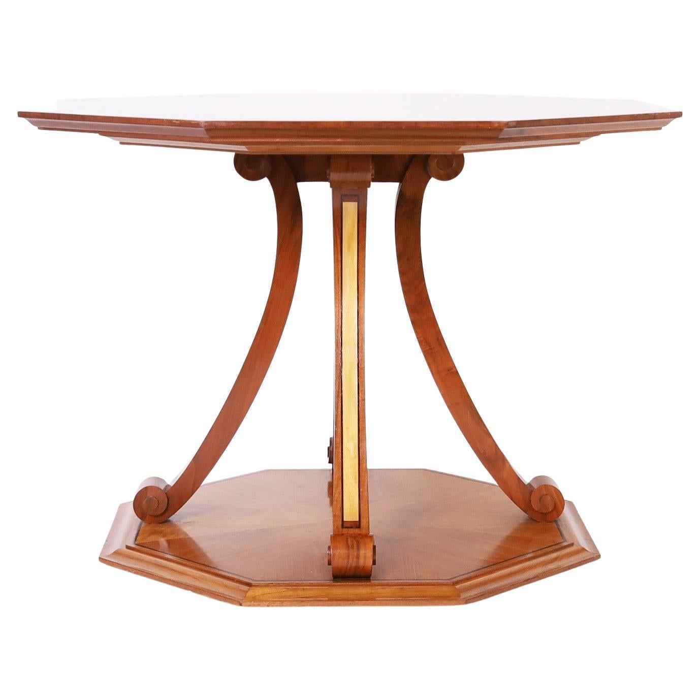 Unusual center table crafted in mahogany and walnut veneer with an octagon form top having a sunburst grain design with a floral border inlaid with Macassar ebony, satinwood, sycamore, and burl wood. The base has scrolled saber legs with inlays and