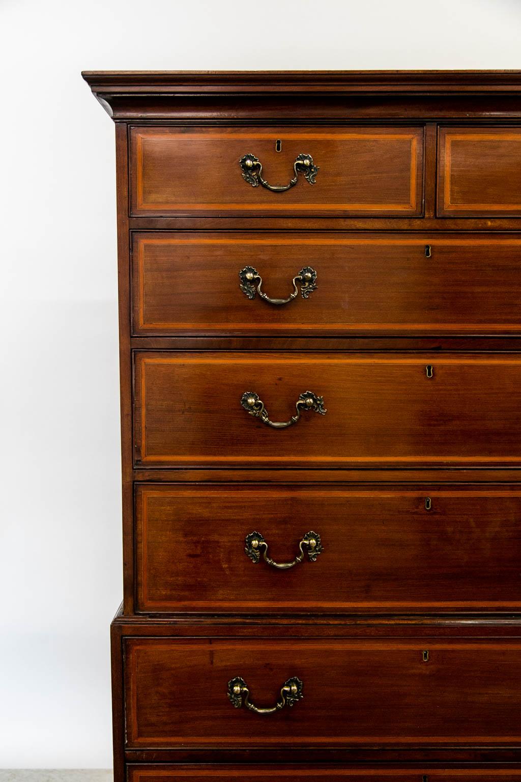 This English mahogany chest on chest has its original hardware that has been highlighted and lacquered for ease of maintenance. The drawers are inlaid with satinwood, ebony, and boxwood.