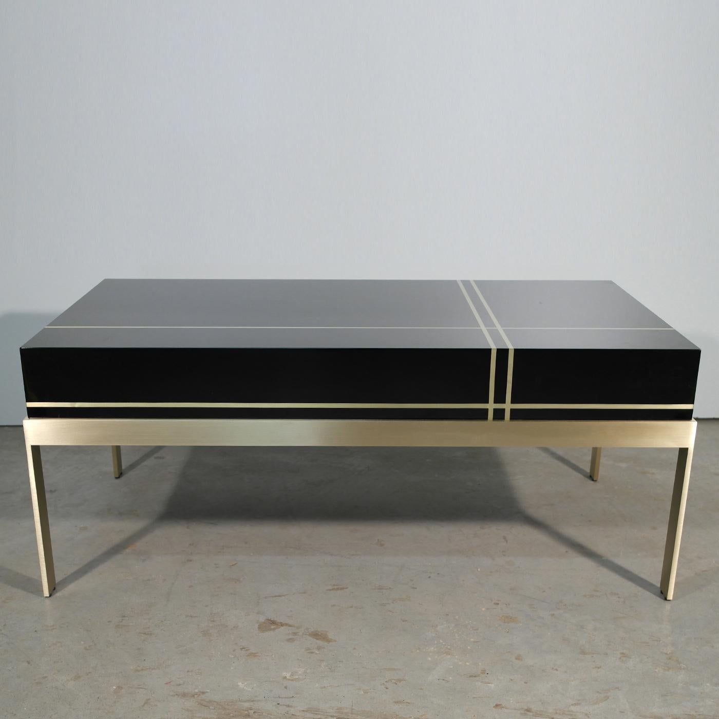 This beautiful coffee table makes a striking addition to any modern living room. Its polished brass base is topped with a black wood veneer top, embellished with decorative brass inlaid detailing. With its sleek lines, glossy textures and