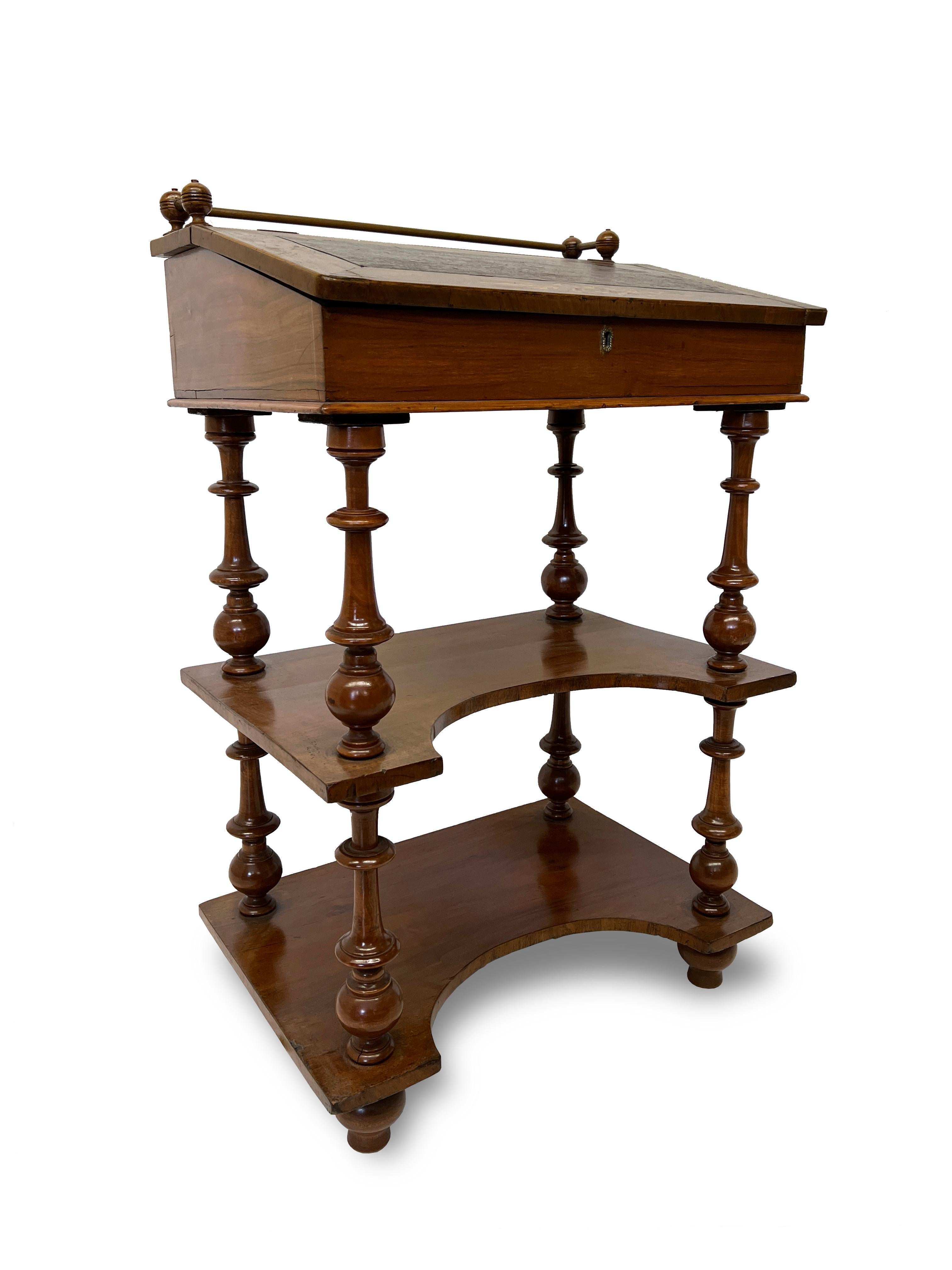 This English inlaid desk or davenport is an excellent addition for any space. It is composed of shelves and has a slant top that lifts to expose a storage compartment. The top has a brass gallery rail with wooden baluster supports. The slant front