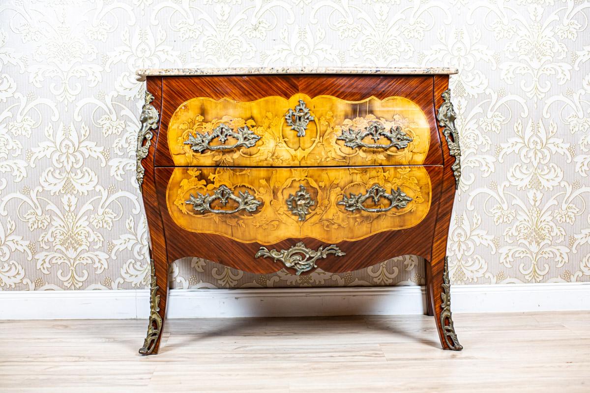 Inlaid French Commode from the 18th-19th Century with Marble Top

We present you this French piece of furniture of the bombe shape.
The corpus hides two drawers and is covered above with a wavy marble top.
Furthermore, the front and sides are