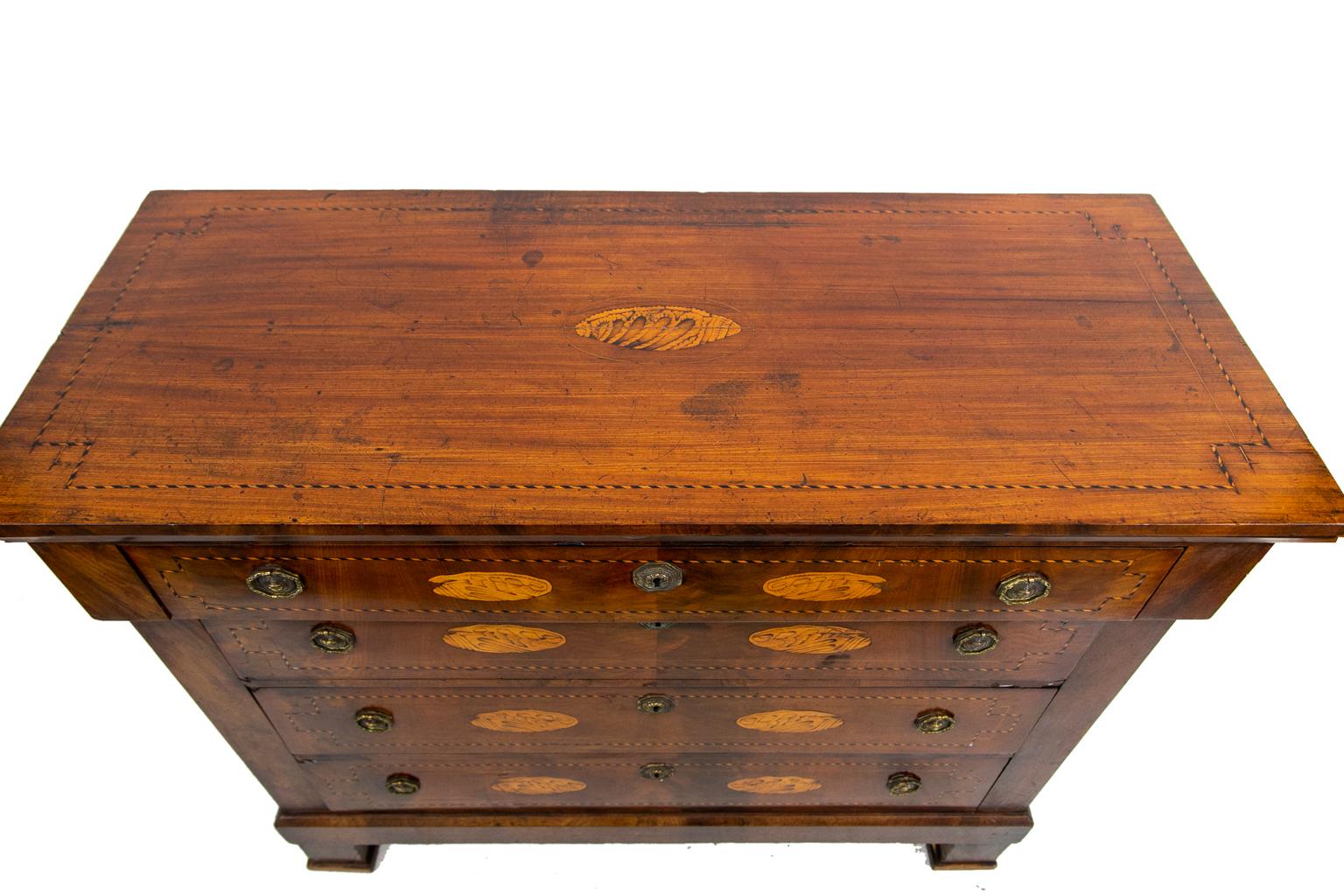 Inlaid French four-drawer chest, with the top and drawers inlaid with ebony and boxwood barber pole inlay, also featuring bookmatched crotch mahogany veneers and double conch shell inlays. The lower drawers and top have interlaced boxwood string