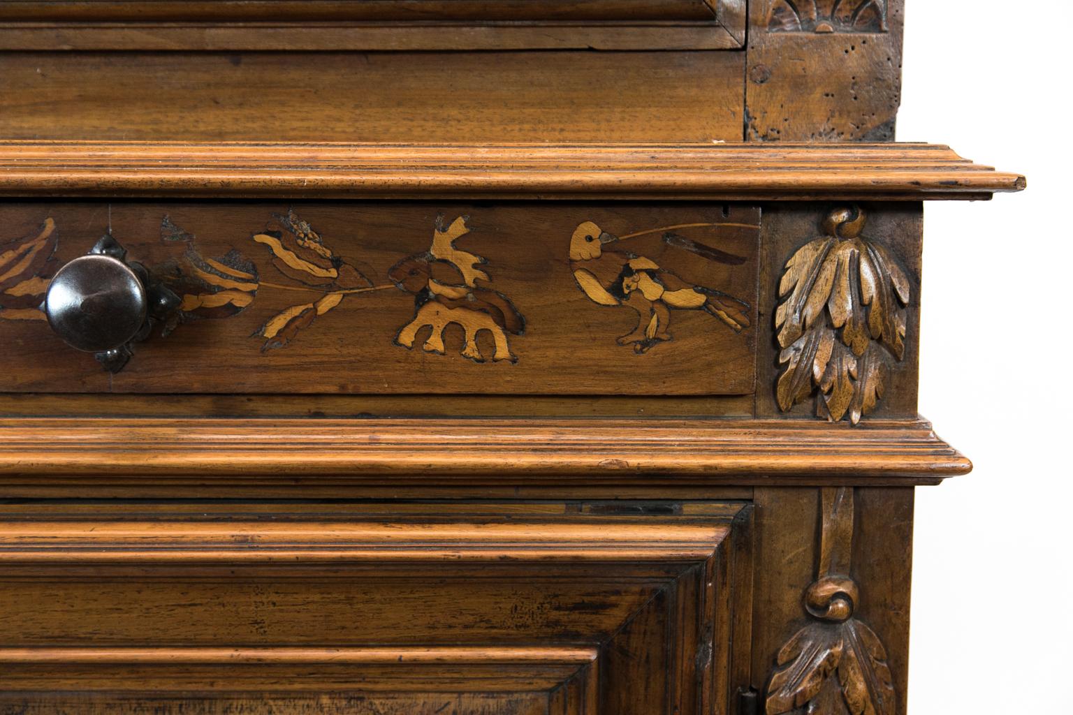 Inlaid French walnut cupboard, with frieze that is inlaid with birds and floral patterns. The doors are inlaid with stylized ducks holding malachite leaves. The upper door is surrounded by incised stylized acanthus carvings. The lower door is
