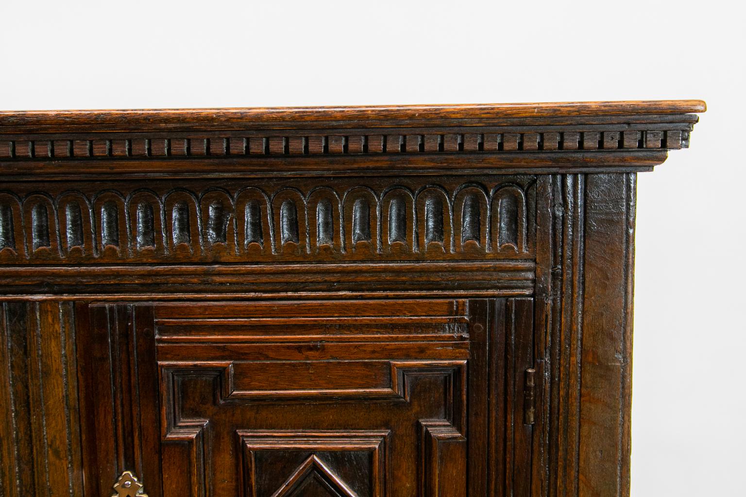 Inlaid geometric Jacobean style court cupboard, with the top having dental molding while the doors and drawers have geometric moldings. The center panel is inlaid with ebony and boxwood bird and floral motifs, two drawers with tear drop pulls. There