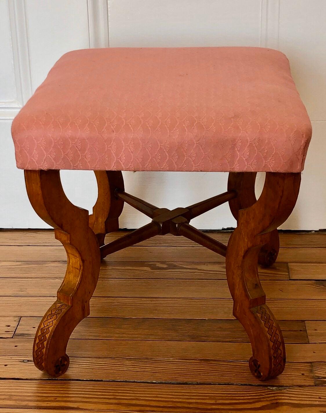 This Biedermeier stool has elegant legs with twist inlay running down the front foot of each leg with inlaid rosettes on each side. The bench has a turned X-stretcher between the legs giving them extra support.