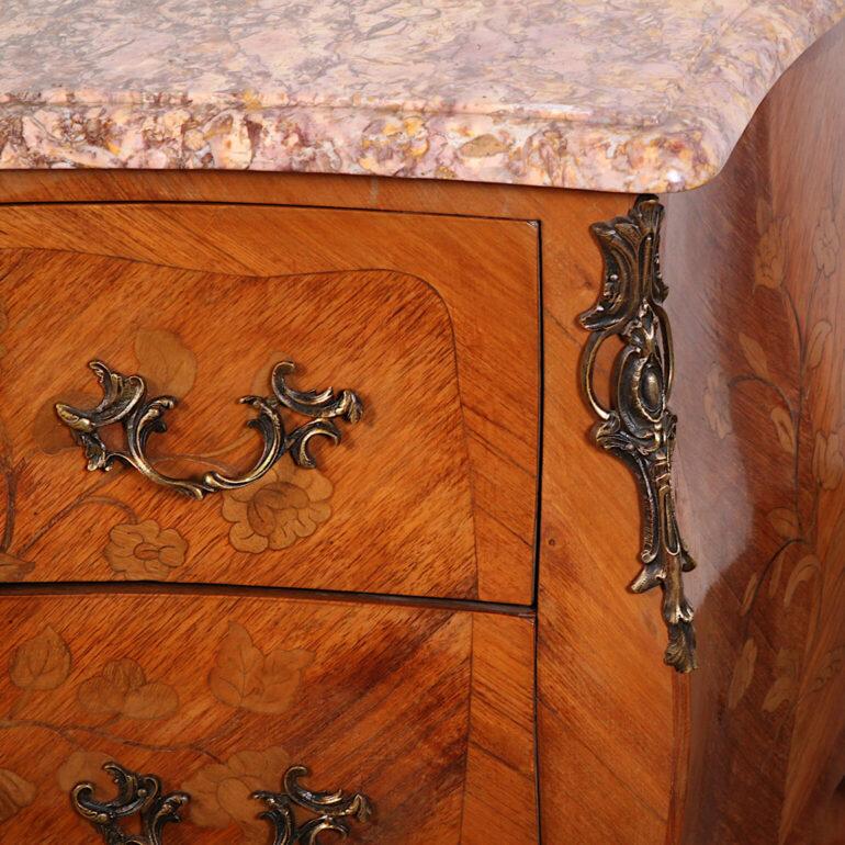Inlaid French early-20th century Louis XV style marble-top 'bombe' commode featuring floral marquetry to the sides and drawer fronts. Original shaped marble top; detailed brass mounts.