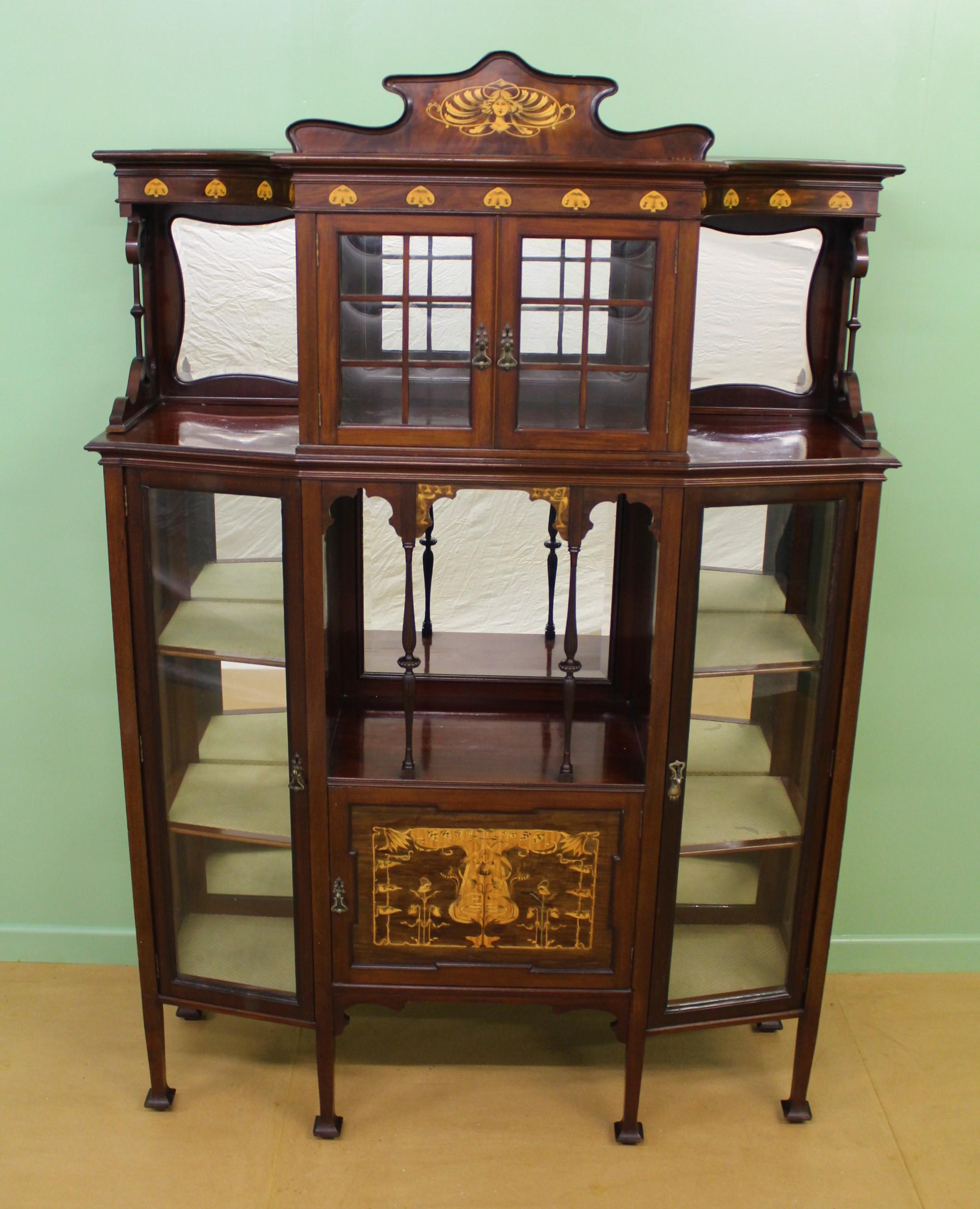 A wonderful display cabinet from the Art Nouveau period. Of very good construction in mahogany and embellished with stylized inlaid motifs in satinwood and boxwood. The top section with a central glazed cabinet fitted with the original panes of