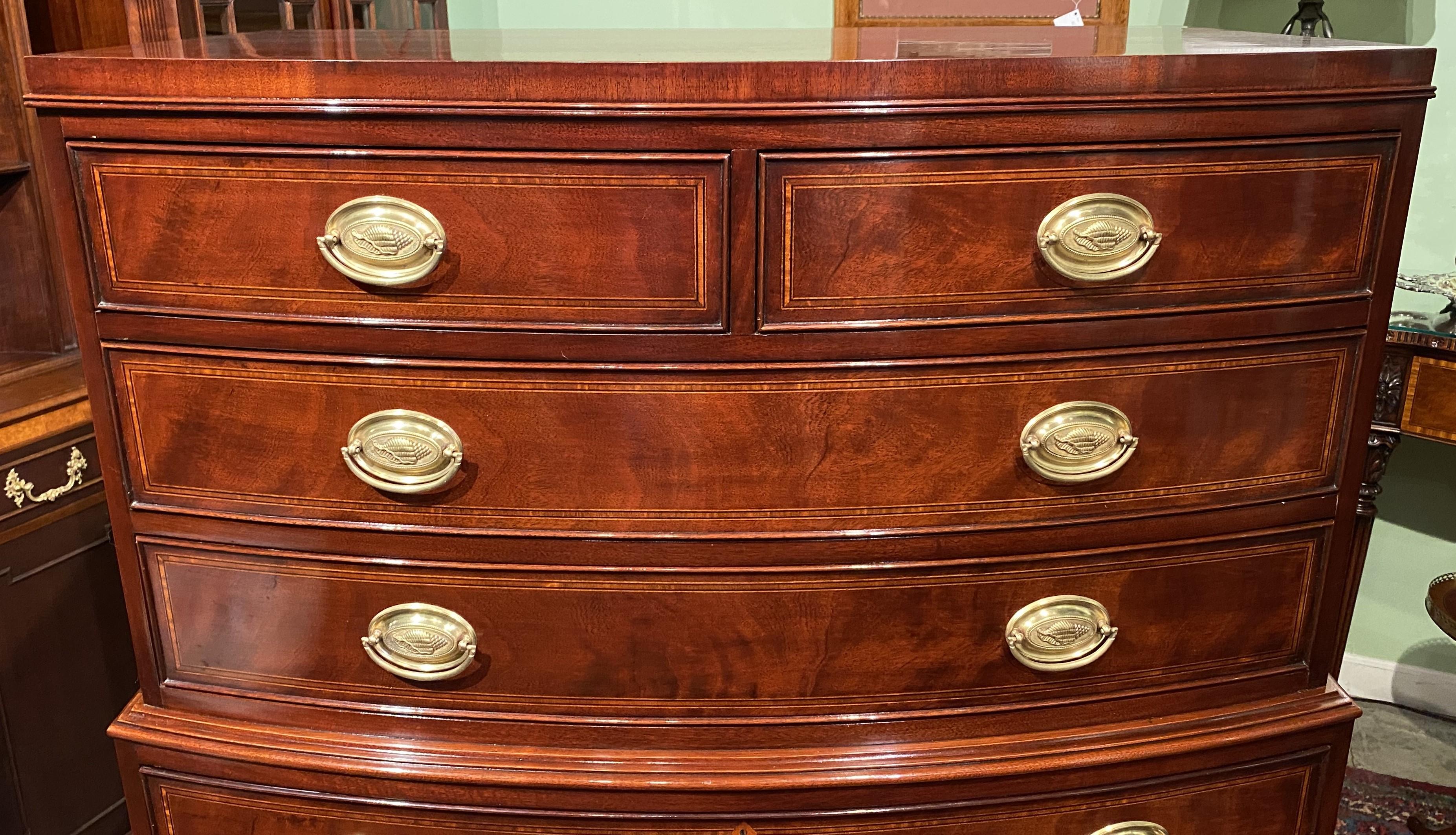 A beautiful one-piece Federal style mahogany bow front tall chest of drawers in a two over six configuration, conforming top, crotched veneer drawer fronts with cockbeading and inlaid borders, adorned with shell decorated oval brass pulls, and a