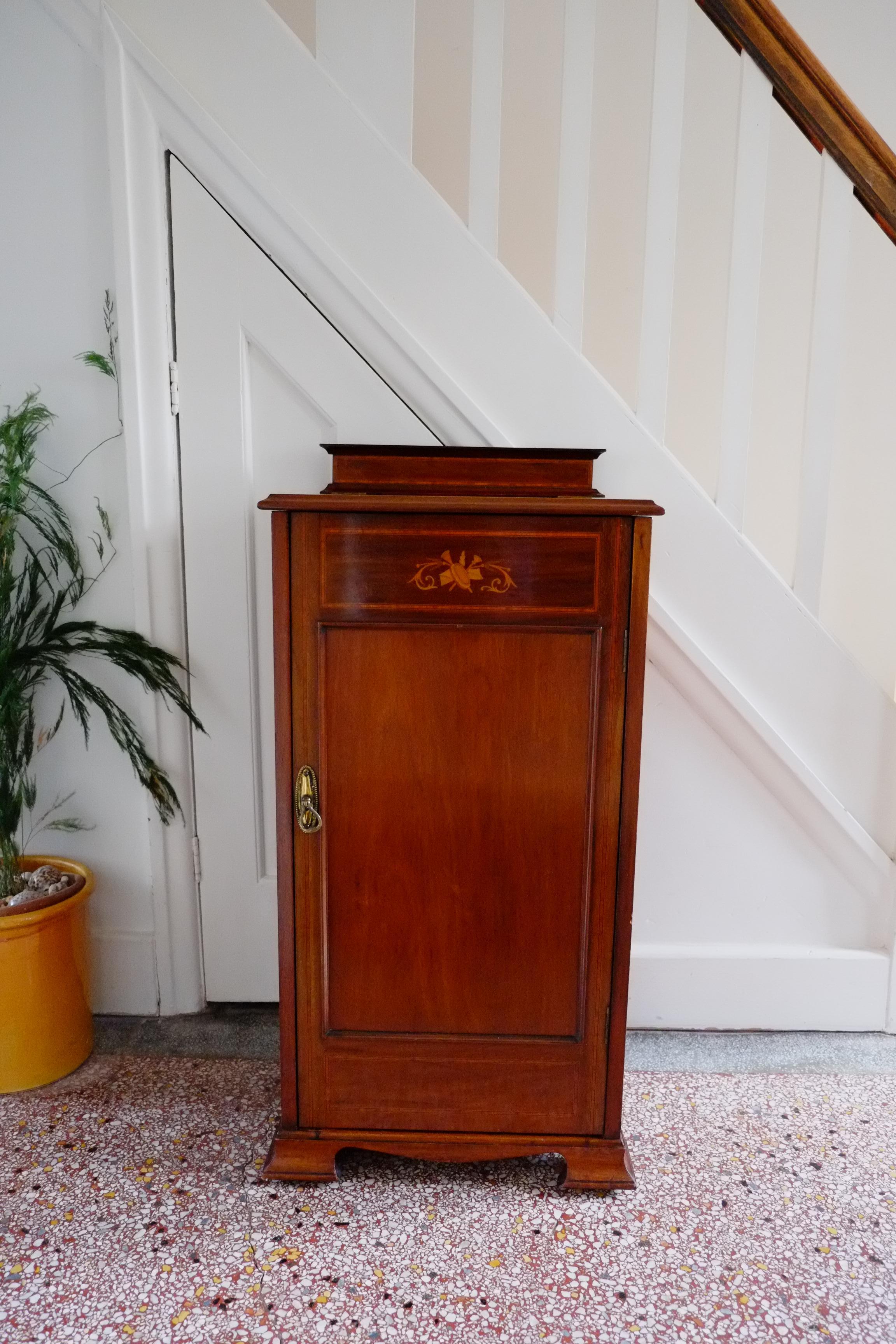 Magnifique meuble à musique anglais en acajou marqueté. Le meuble est doté d'une porte unique et d'un couvercle relevable, le tout avec une élégante bordure en marqueterie et un petit décor d'instruments de musique en haut de la porte. Le meuble a