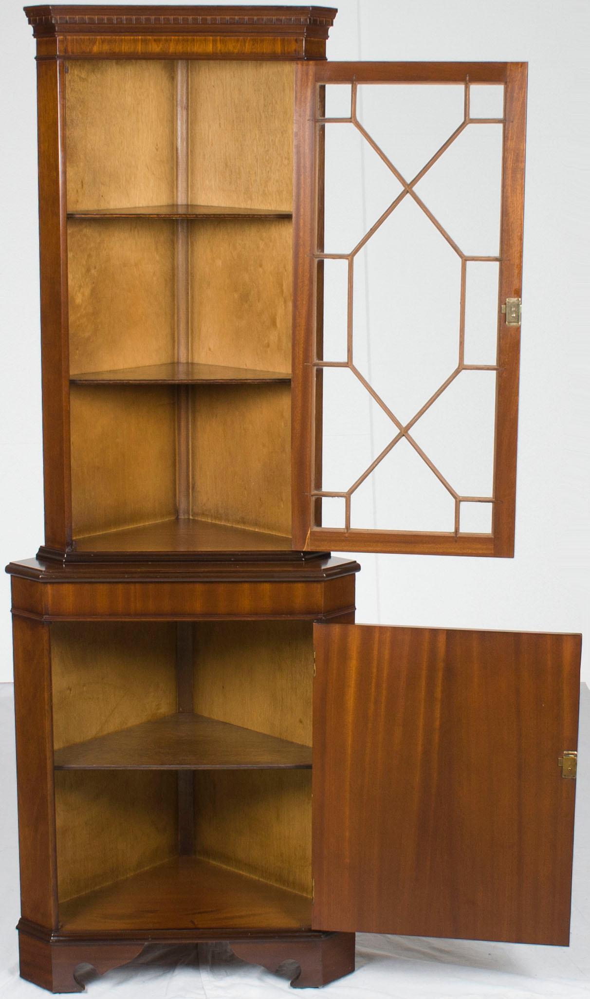This antique style mahogany corner cabinet was crafted in England around 1960. Today, the mahogany retains a gorgeous complexion and a striking grain, particularly on the lower cabinet door. Both cabinet doors operate with an accompanying key, while