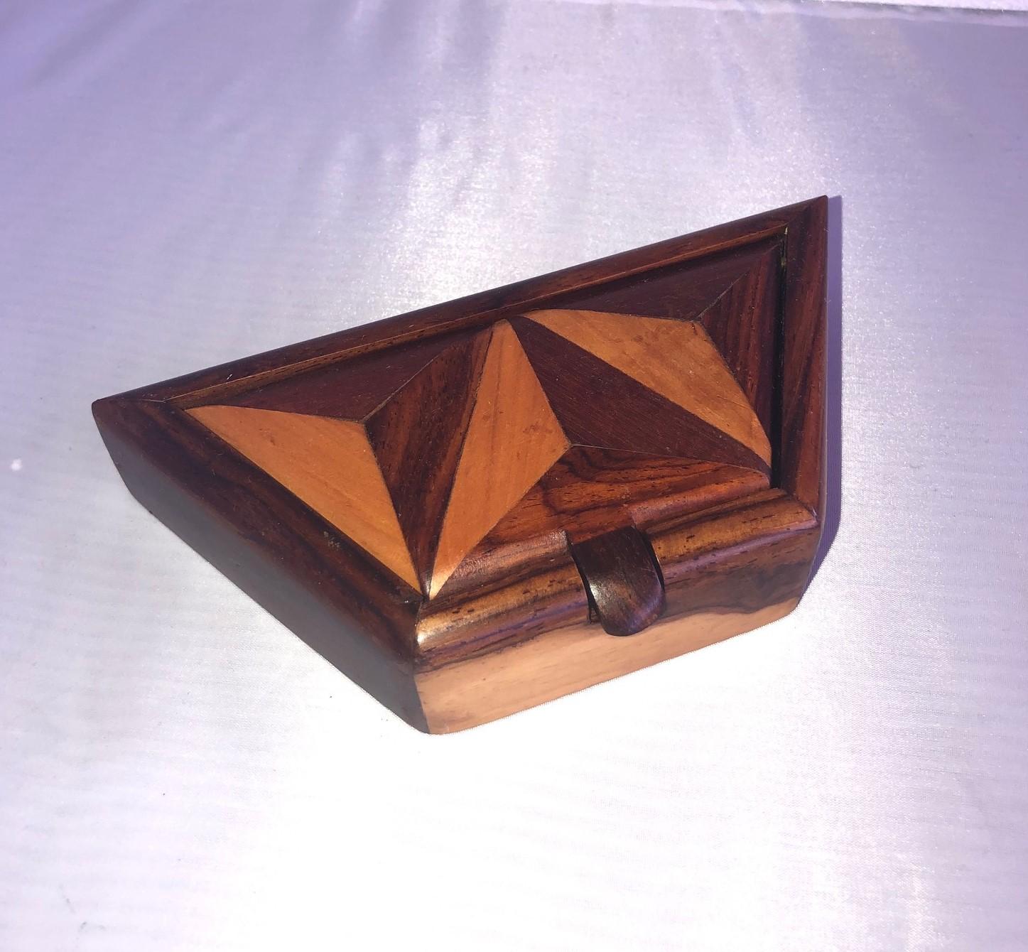 Beautiful and unique handcrafted trinket box made of inlaid mixed woods (mahogany, walnut, burl wood, rosewood and maple), circa 1970s. The piece has a trapezoid shape and a attached lid that rotates up to open. The bottom of the box is felt lined. 