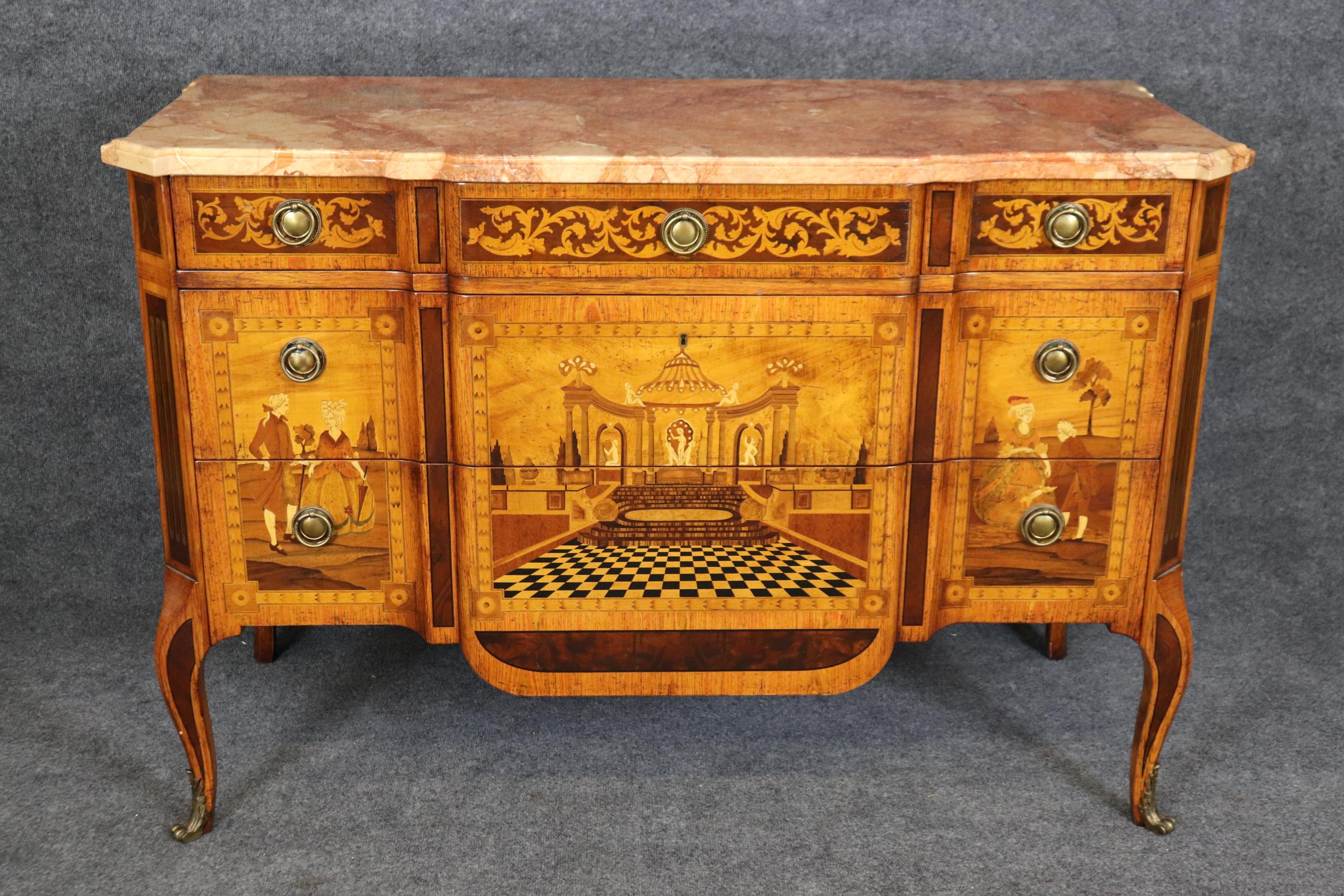 Si tratta di una spettacolare commode intarsiata Baggia Annico of Italy. Il mobile è stato progettato in stile Luigi XV e presenta una scena di cortile ad illusione ottica (op-art) con figure in piedi sopra la corte. Il livello di competenza