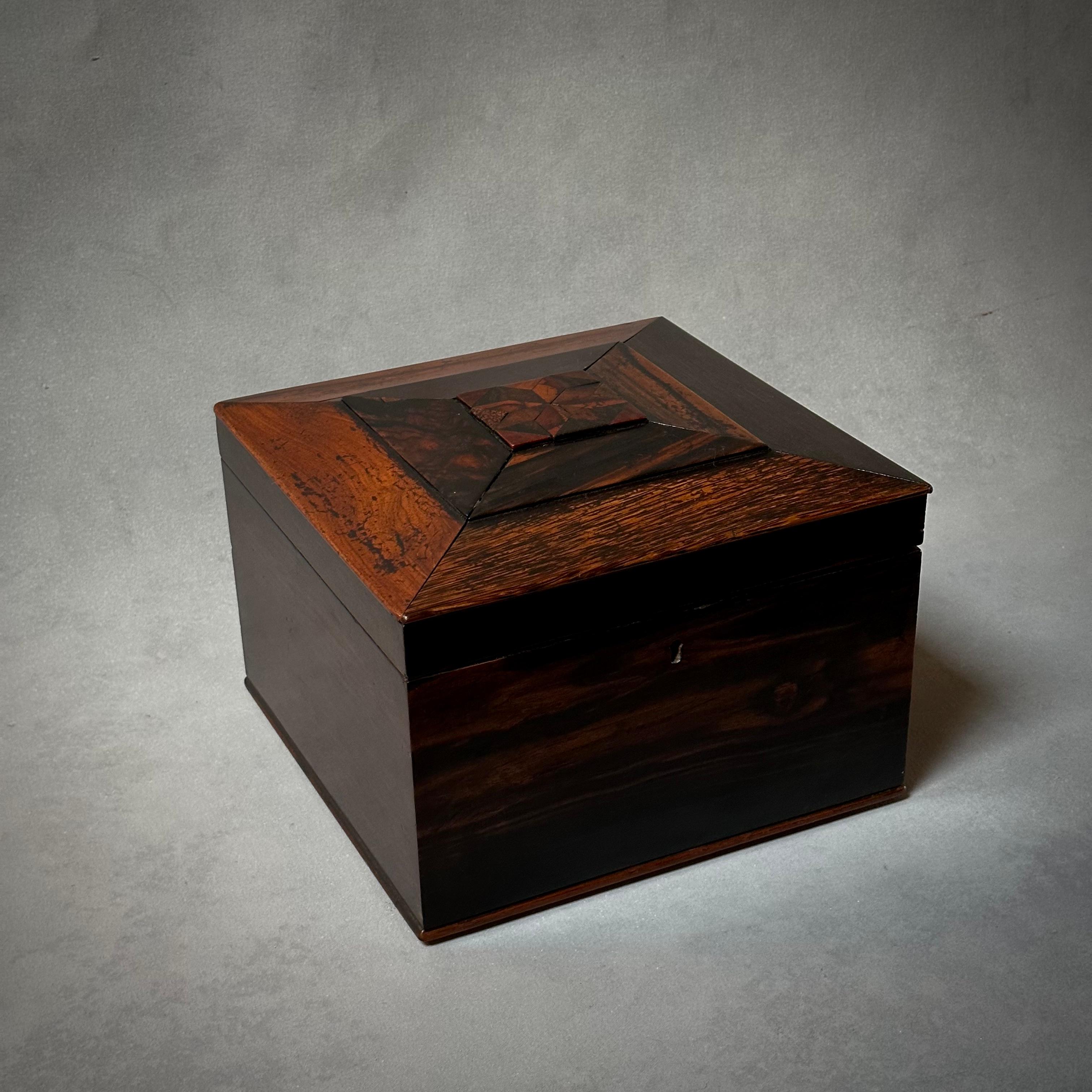 19th Century English rosewood and mahogany square lidded box featuring decorative inlaid top with graphic beveling. A subtle, handsome piece with exquisite detailing. 

England, circa 1860

Dimensions: 11W x 11.5D x 7.5H