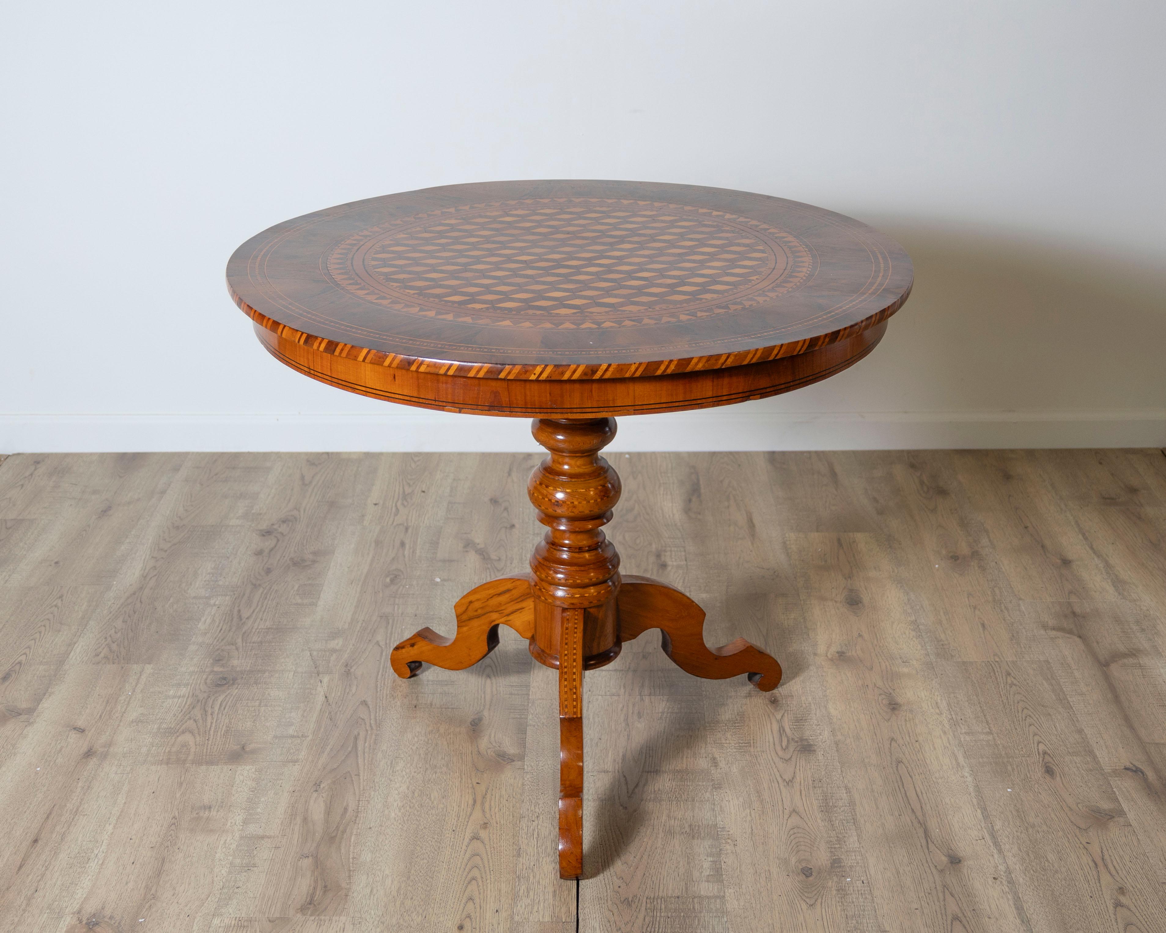 Cette table ronde italienne de la fin du XIXe siècle est une célébration de la maîtrise de la marqueterie et de la géométrie visuelle. La surface en placage de noyer présente un exemple extraordinaire de Tarsia Rolese, une technique d'incrustation